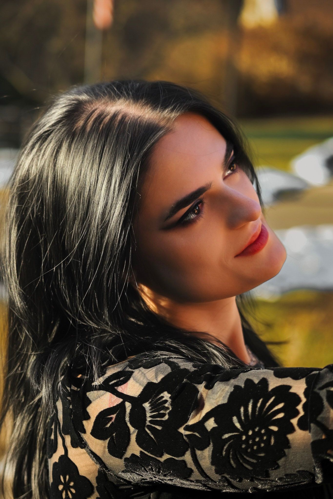 A profile silhouette of a woman with red lipstick against a golden autumn background creates a dramatic contrast.