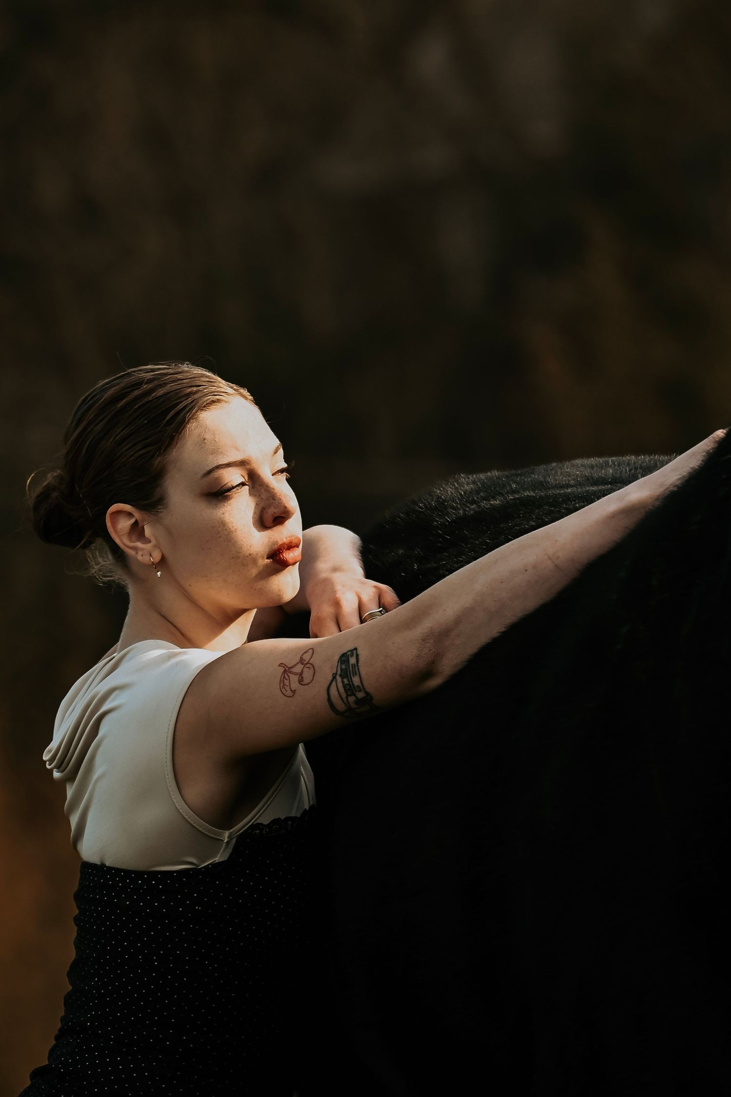 A dancer in white top performs a dramatic arm movement sequence against a dark background.