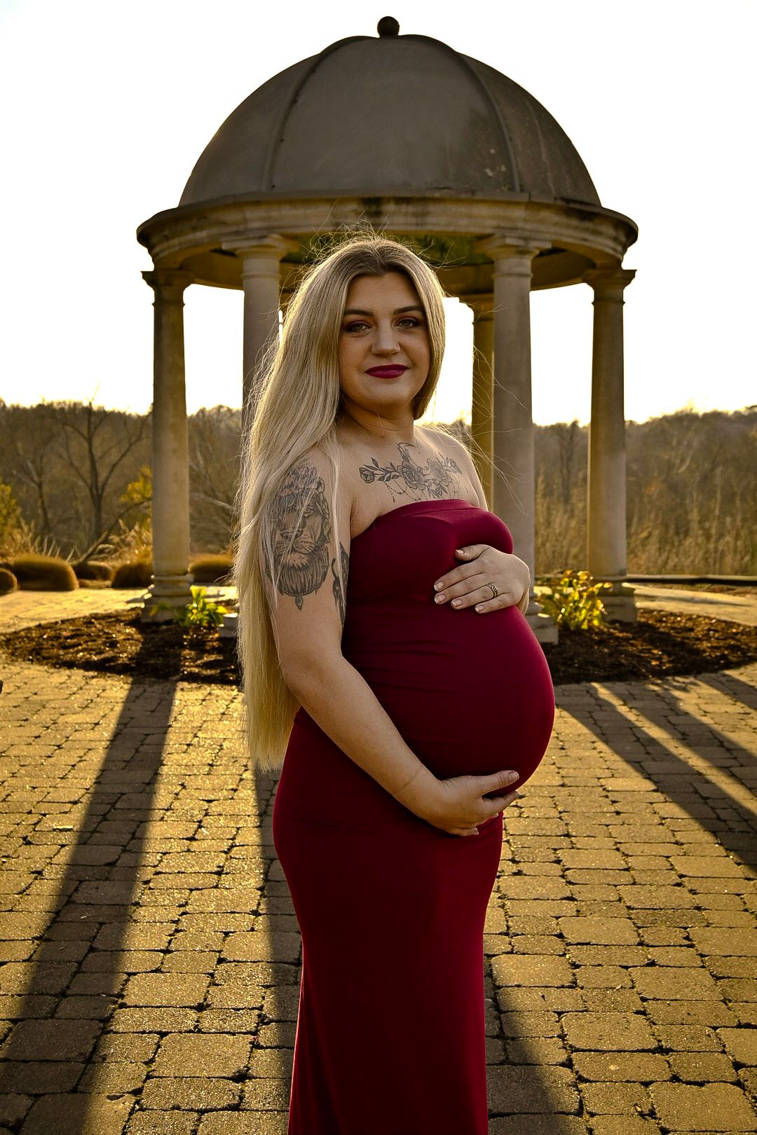 Maternity photoshoot at sunset with classical columns and stone path.