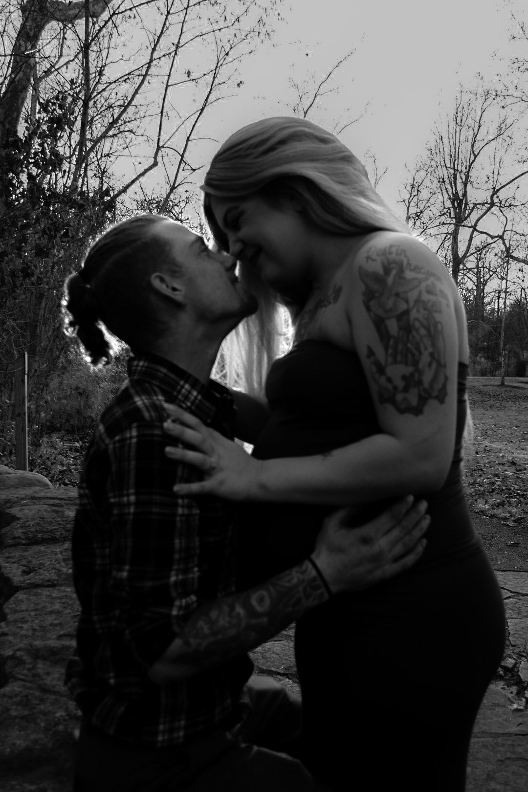 A romantic black and white photo of a couple embracing outdoors.