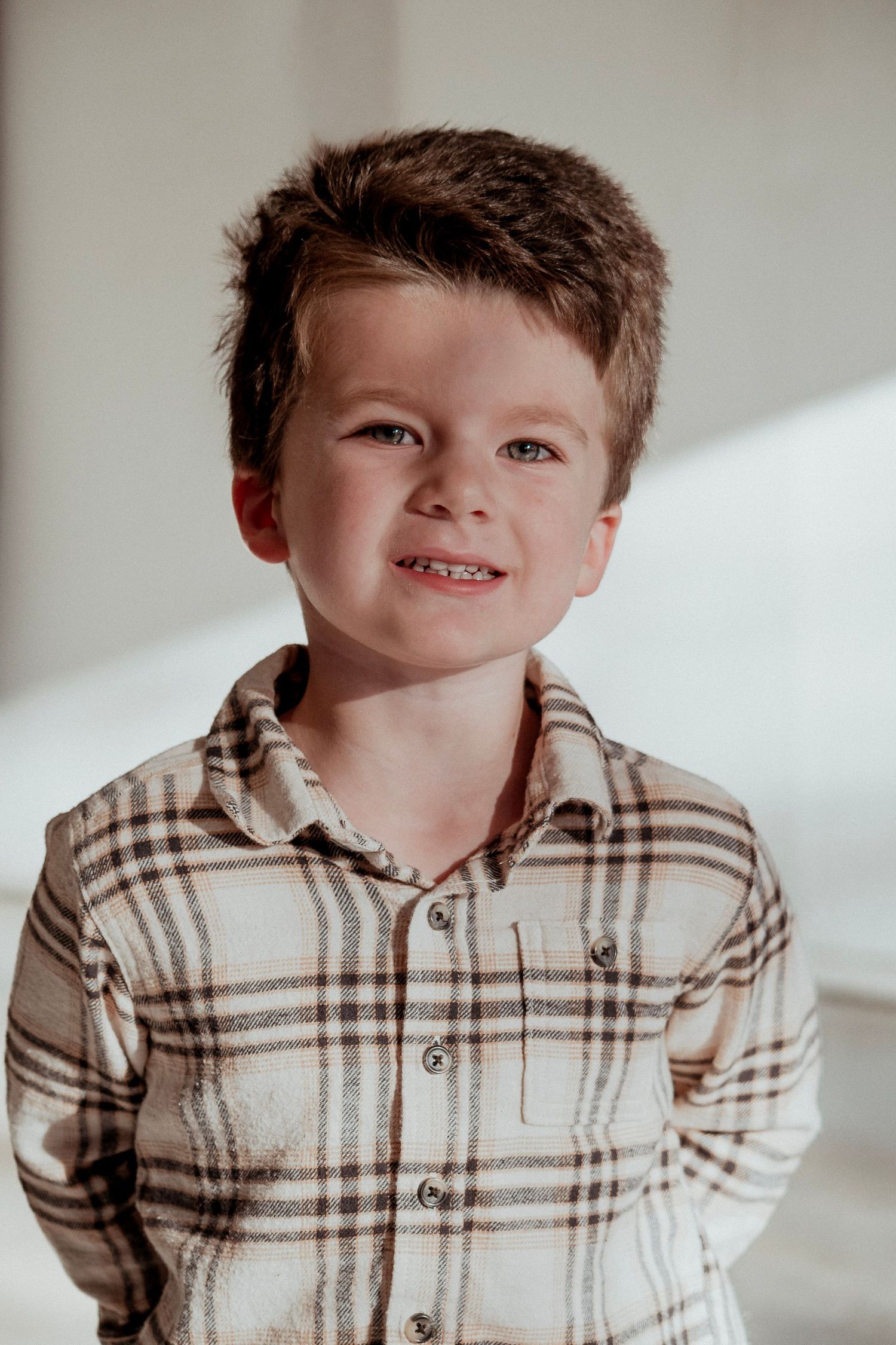 A series of five photos showing a young child wearing a brown and white plaid button-up shirt in different poses.