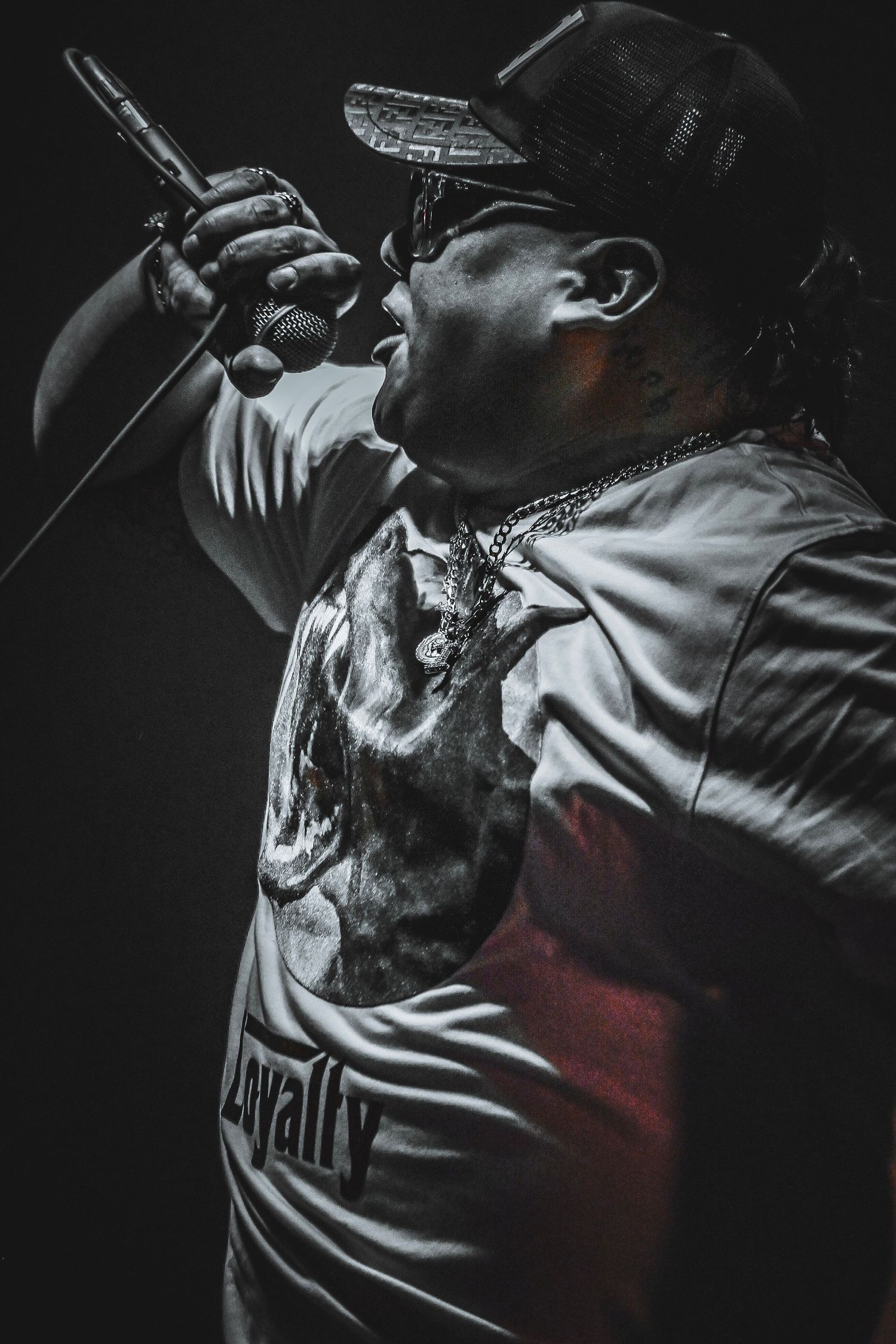 Dramatic monochrome performance shot with red lighting effects and a microphone in focus.