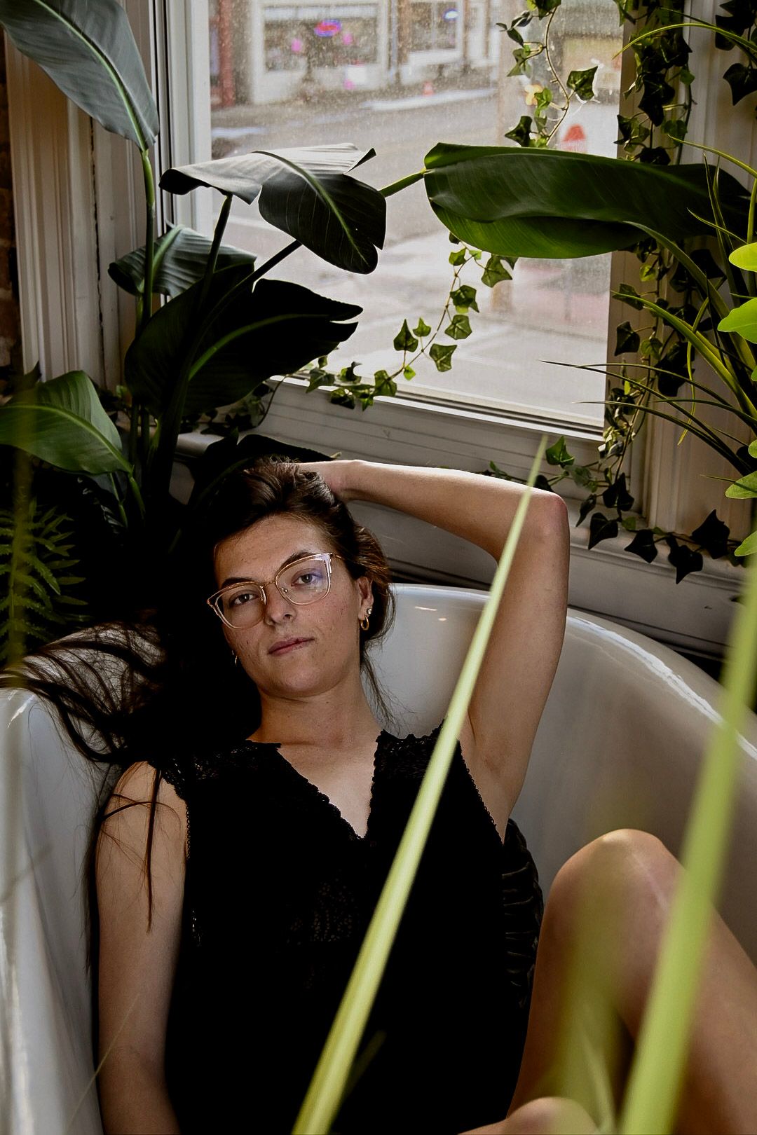 Indoor portrait series with houseplants and natural window lighting creating a peaceful atmosphere.