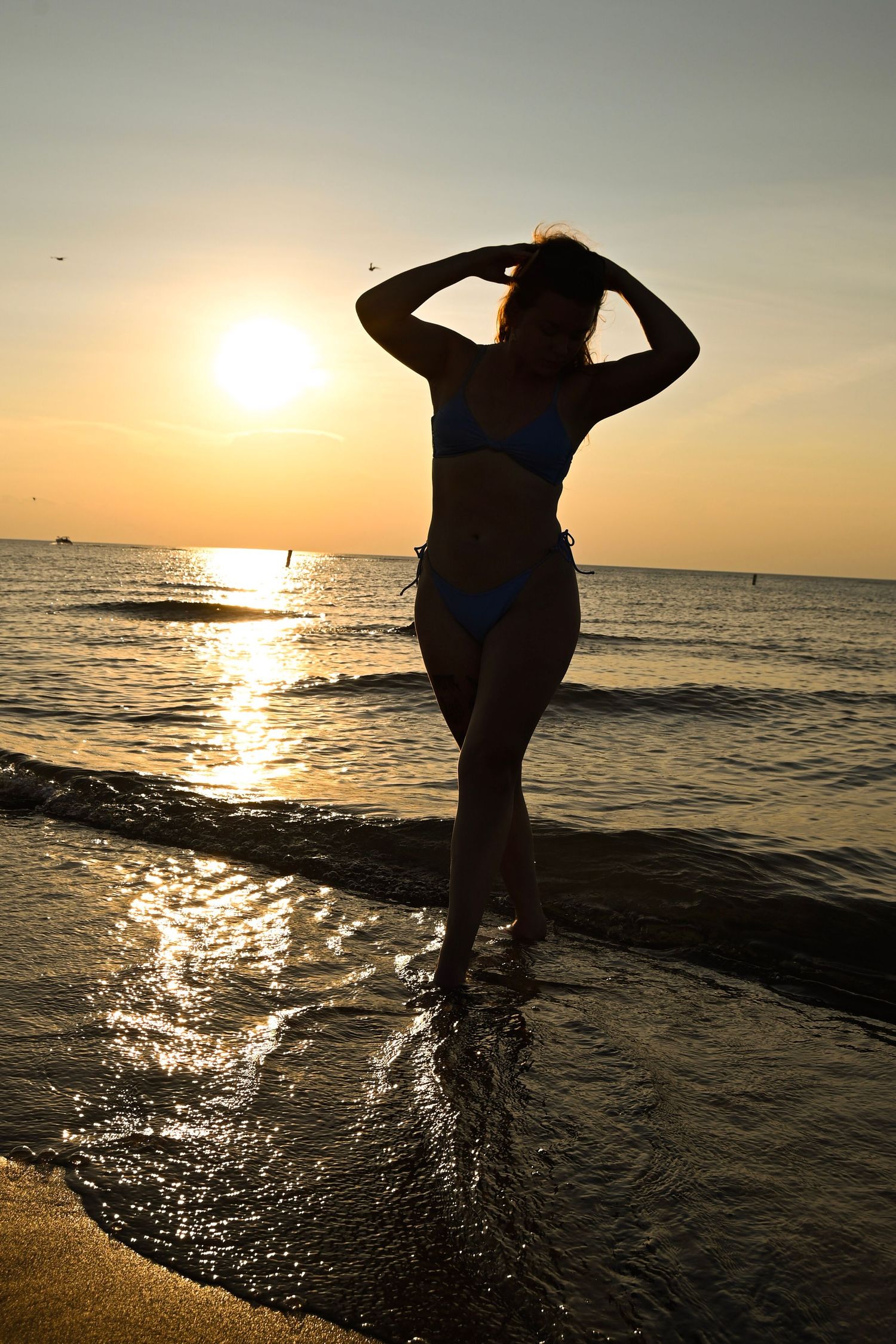 Silhouettes of people playing and splashing at beach during golden sunset.