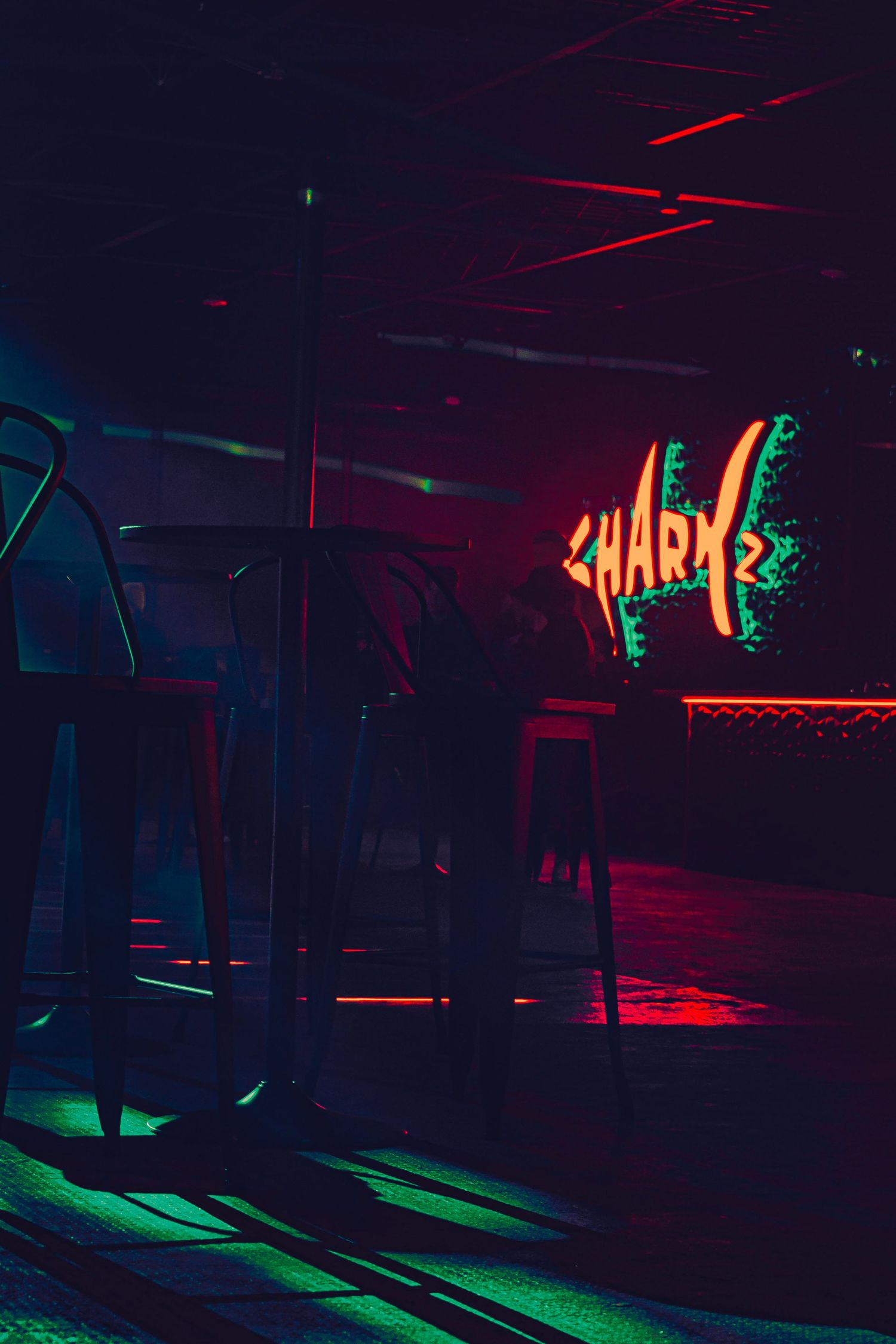 Dark nightclub interior with neon red and green lighting effects creating a moody atmosphere.