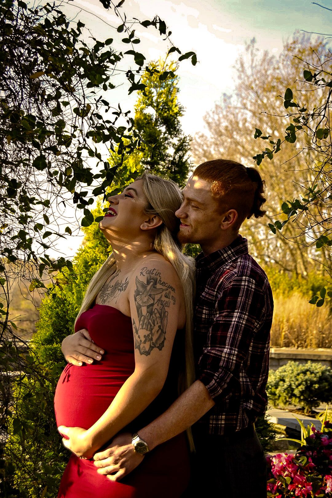 A romantic couple embraces outdoors during golden hour in a garden setting.