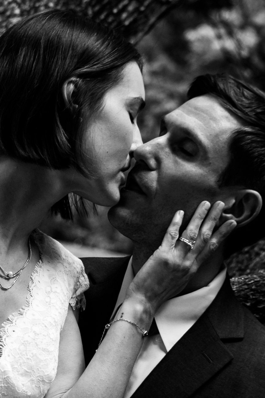 Black and white wedding photo of bride and groom sharing a tender kiss, bride gently holding grooms face.