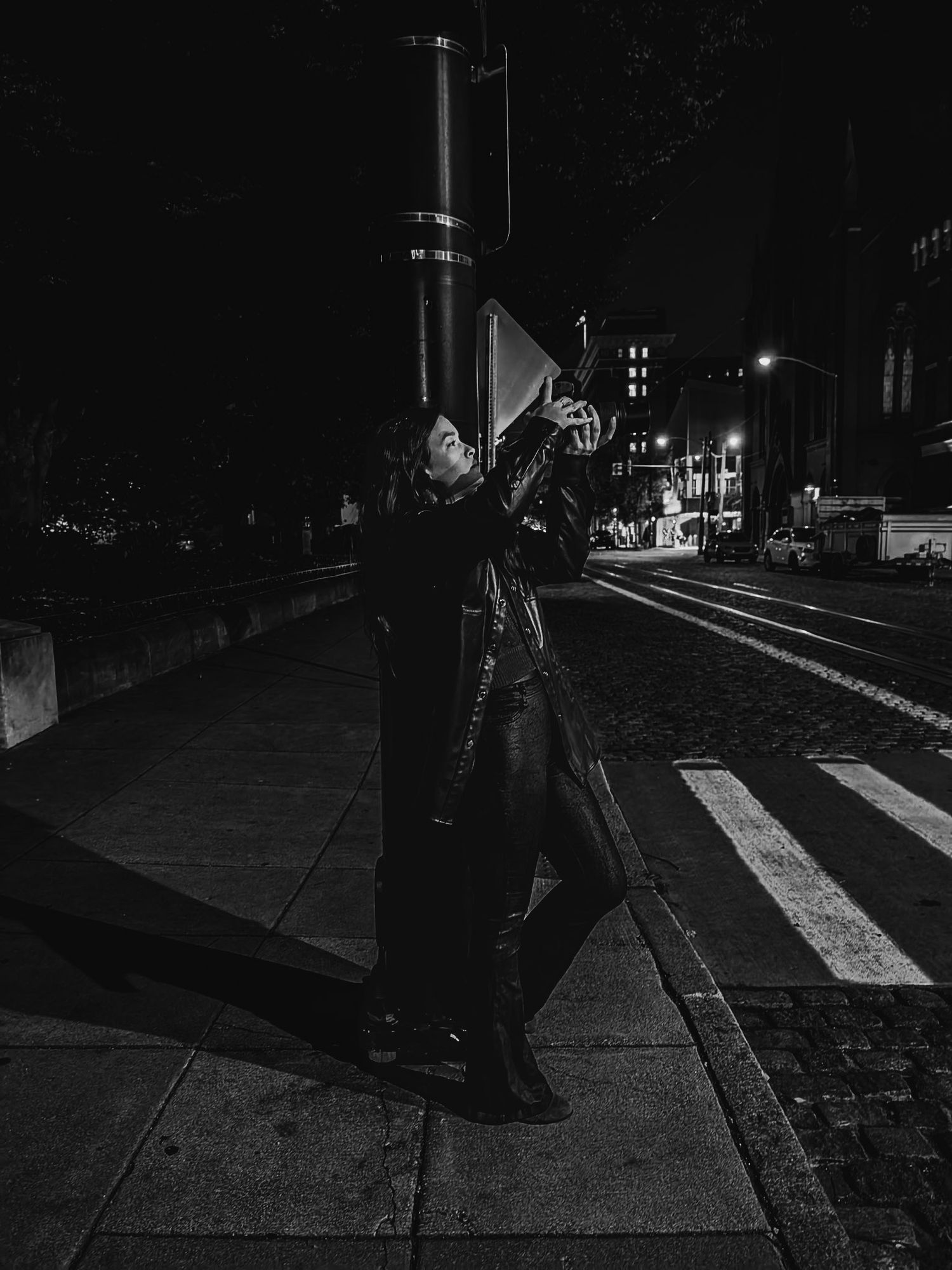 Person holding megaphone on city street at night in dramatic black and white composition.