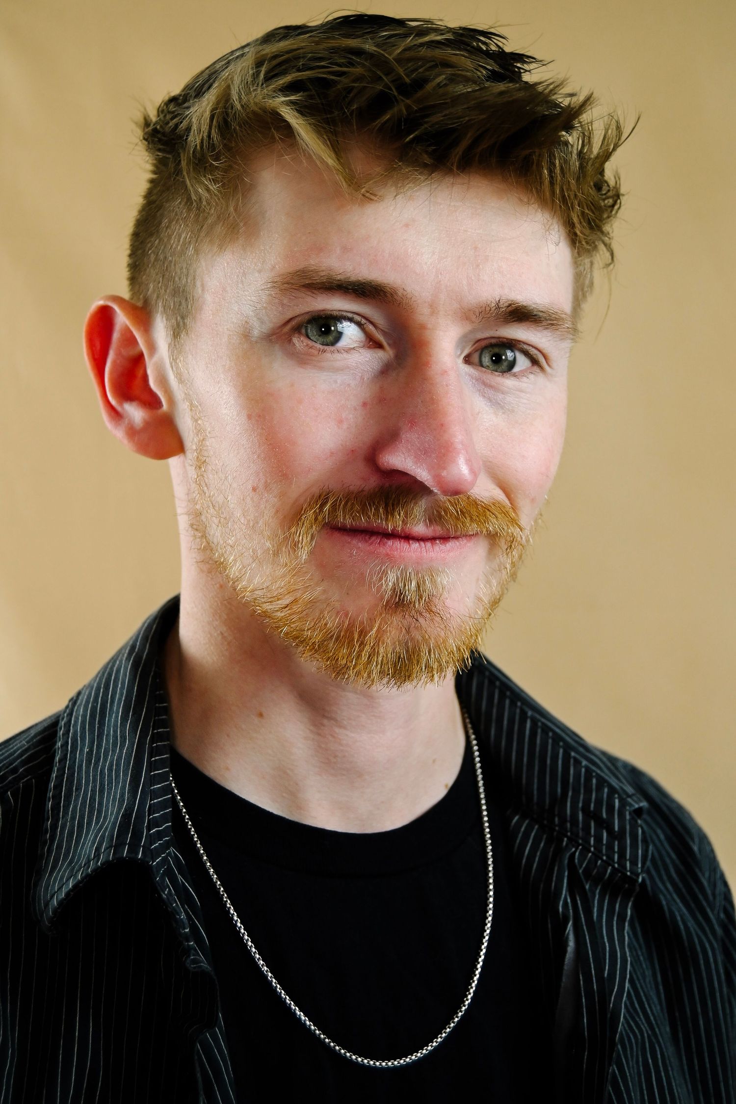 A sequence of close-up portraits showing a person with ginger facial hair wearing a black shirt and silver chain necklace.
