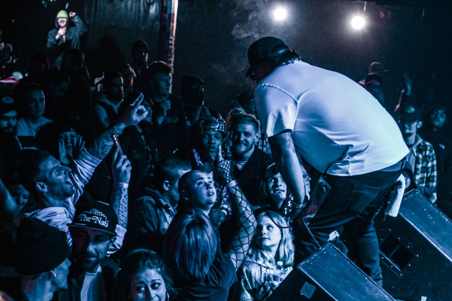 Concert crowd silhouetted against bright stage lights in blue tones.