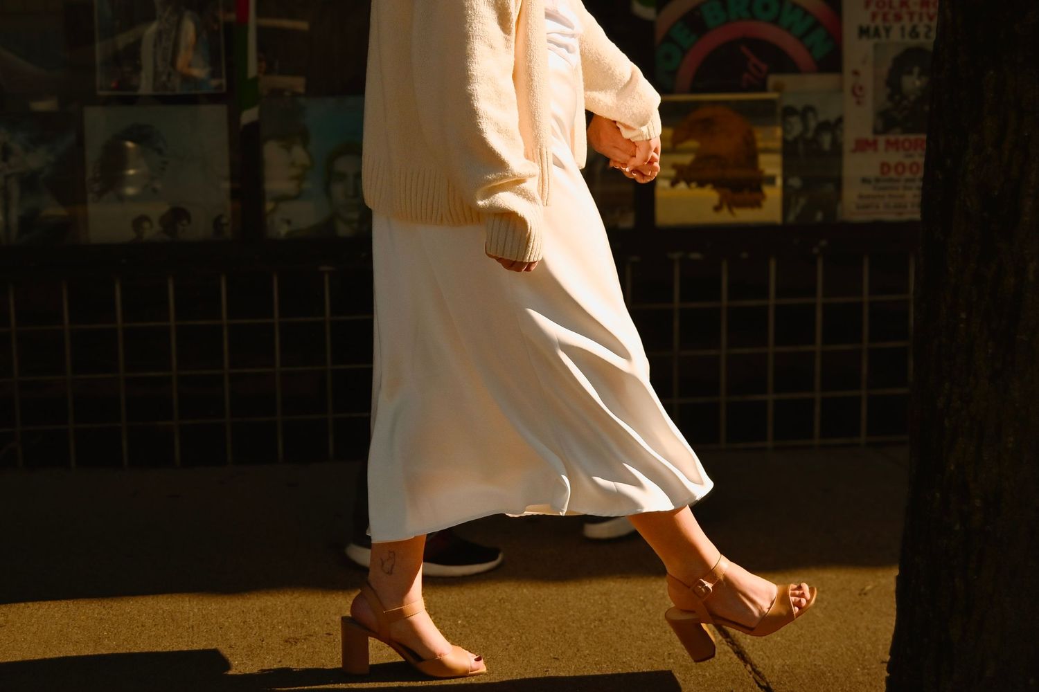 A person in white clothing practices martial arts moves in a dimly lit studio space.