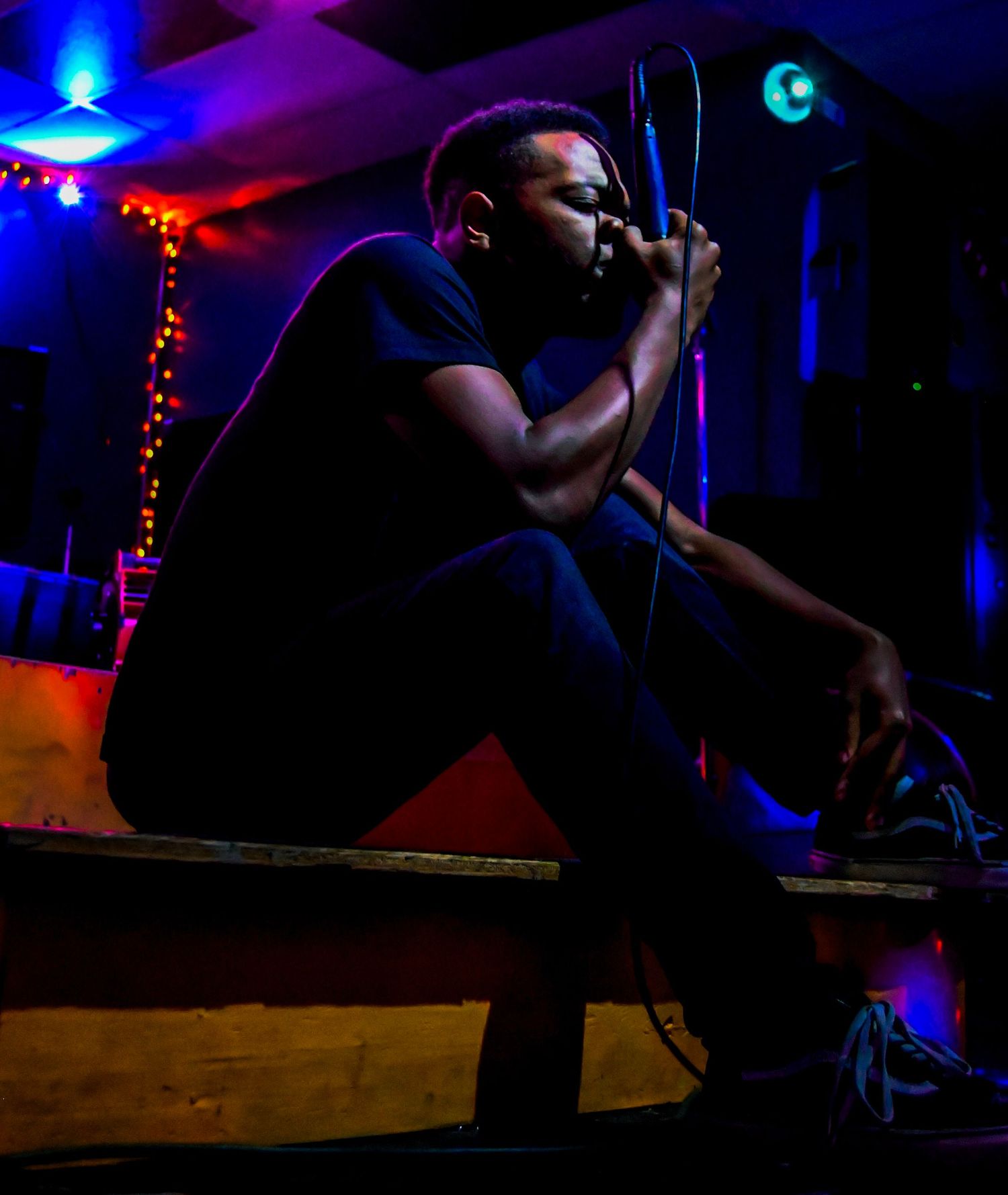 A silhouetted performer singing on stage with dramatic blue and purple lighting.