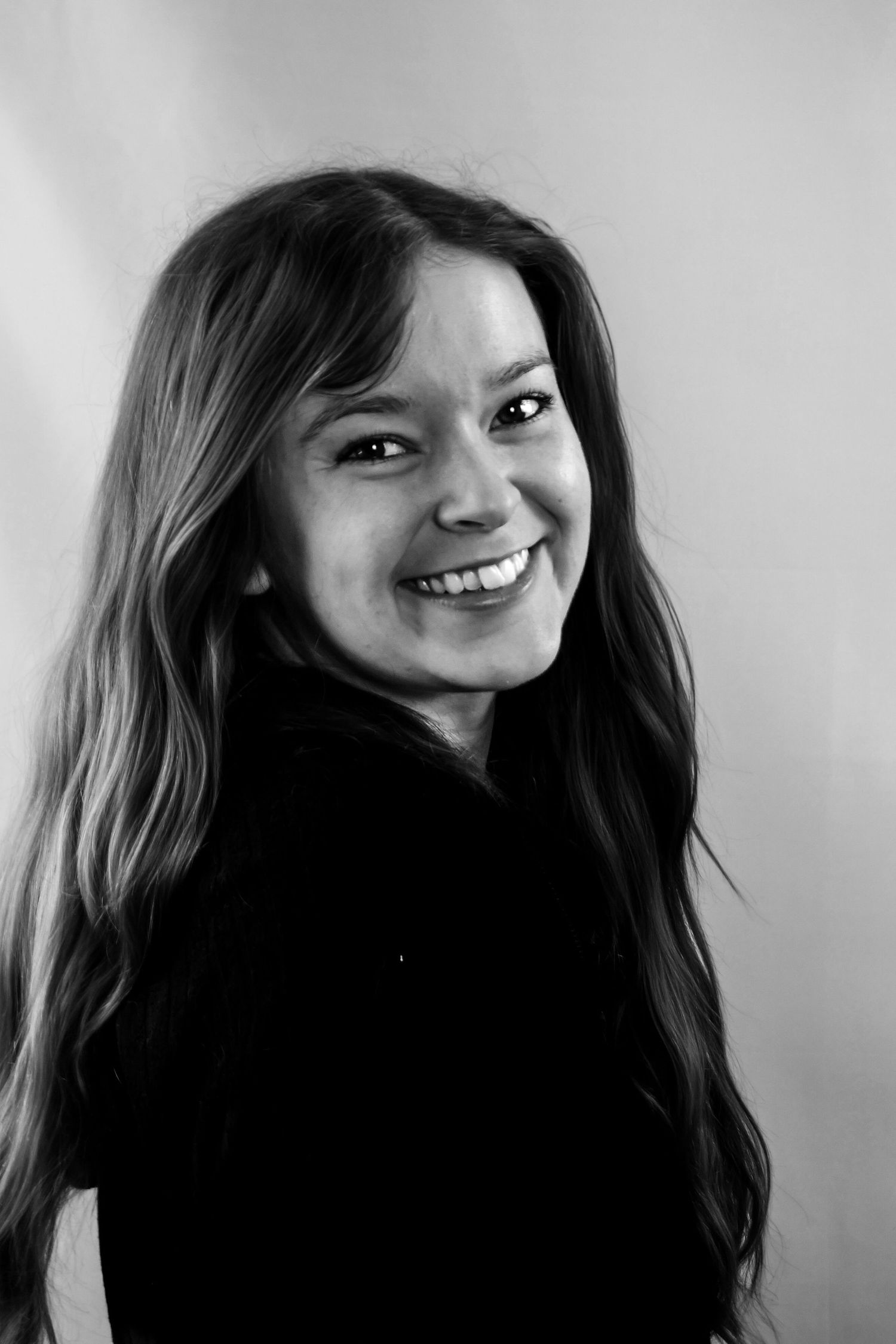 A series of black and white portraits showing a person with long dark hair smiling and posing in different expressions.