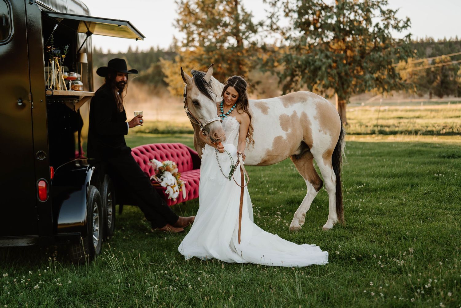 A rustic barn wedding scene with horses grazing in the golden afternoon light.