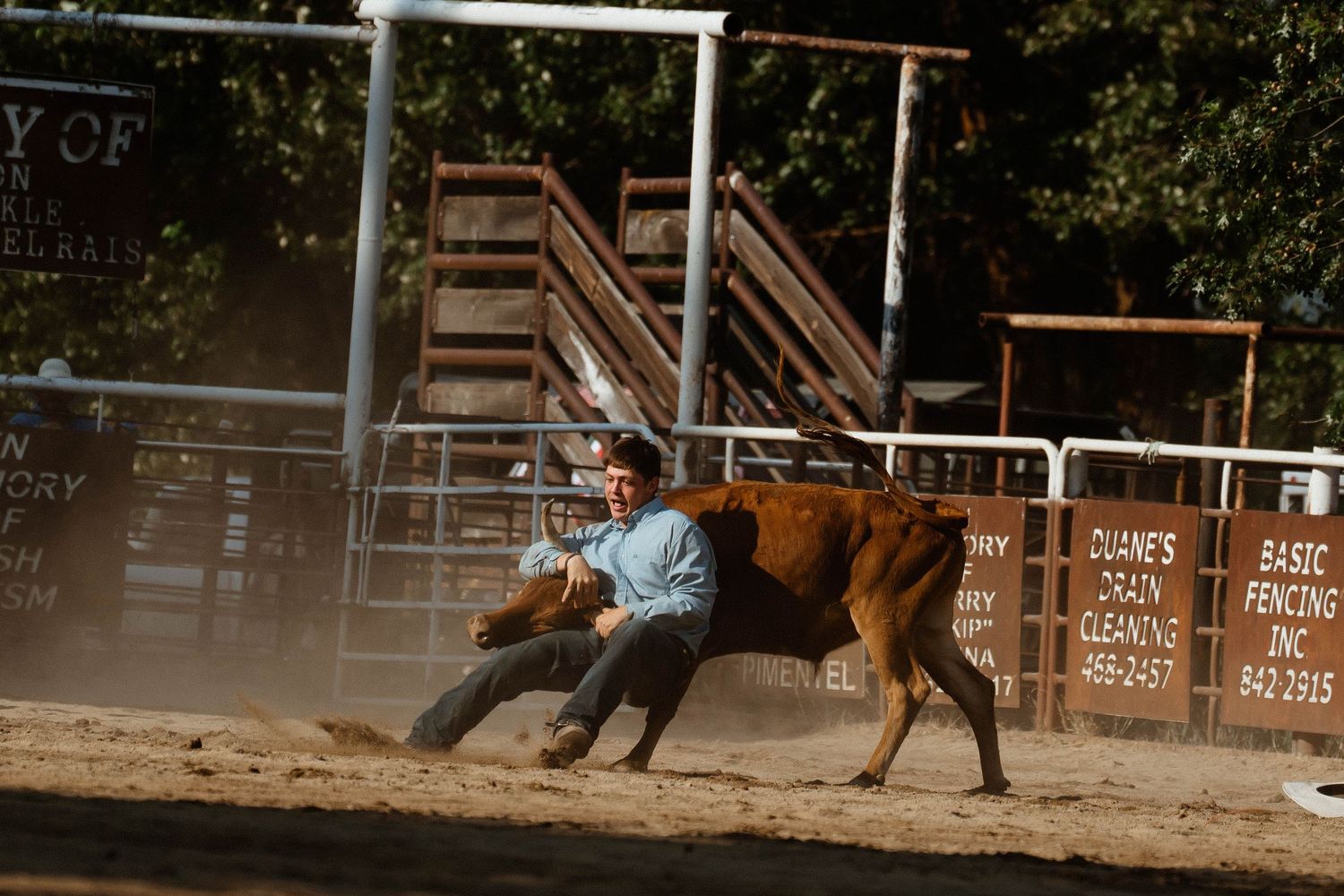 Rodeo competition scene with riders competing in an outdoor arena.