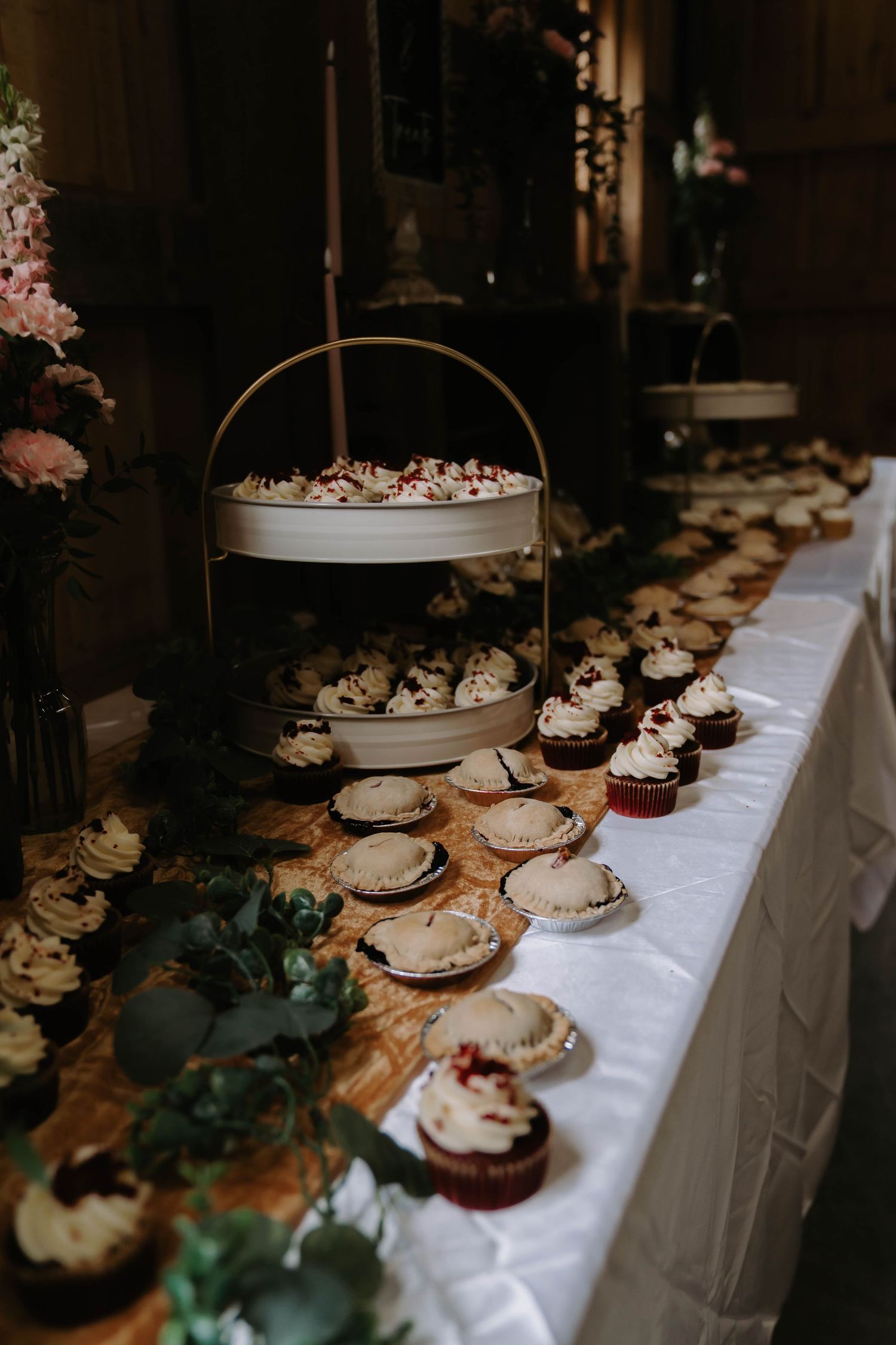Elegant wedding reception dessert table with cupcakes and floral decorations.