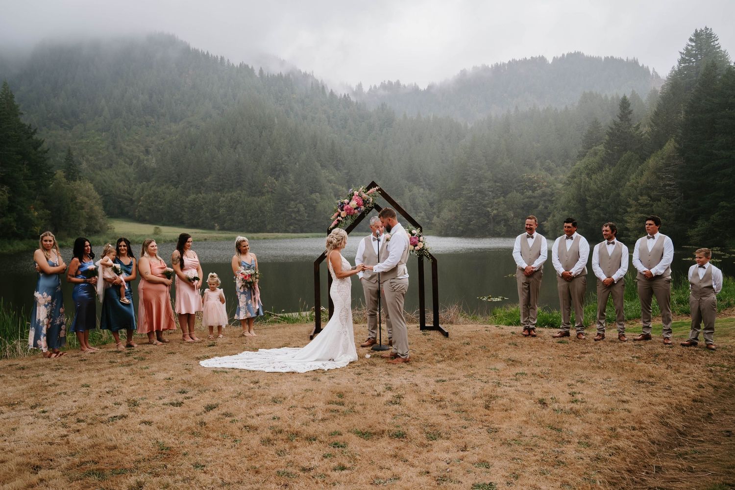 Panoramic view of mountain landscape with wedding ceremony setup and guests.