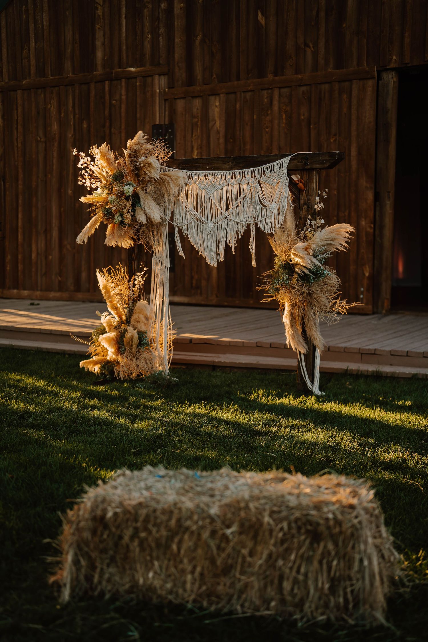 Hay bales and bohemian wedding decorations against a wooden barn backdrop.