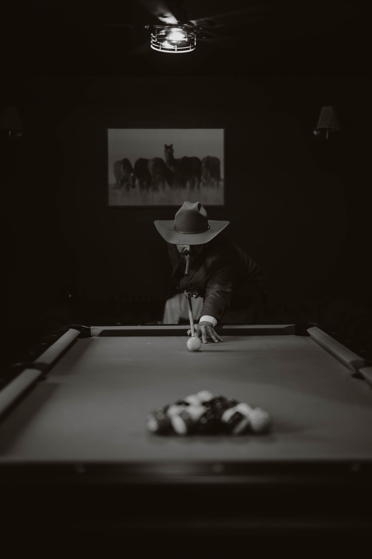 Moody black and white image of a pool table setup in a dimly lit room.