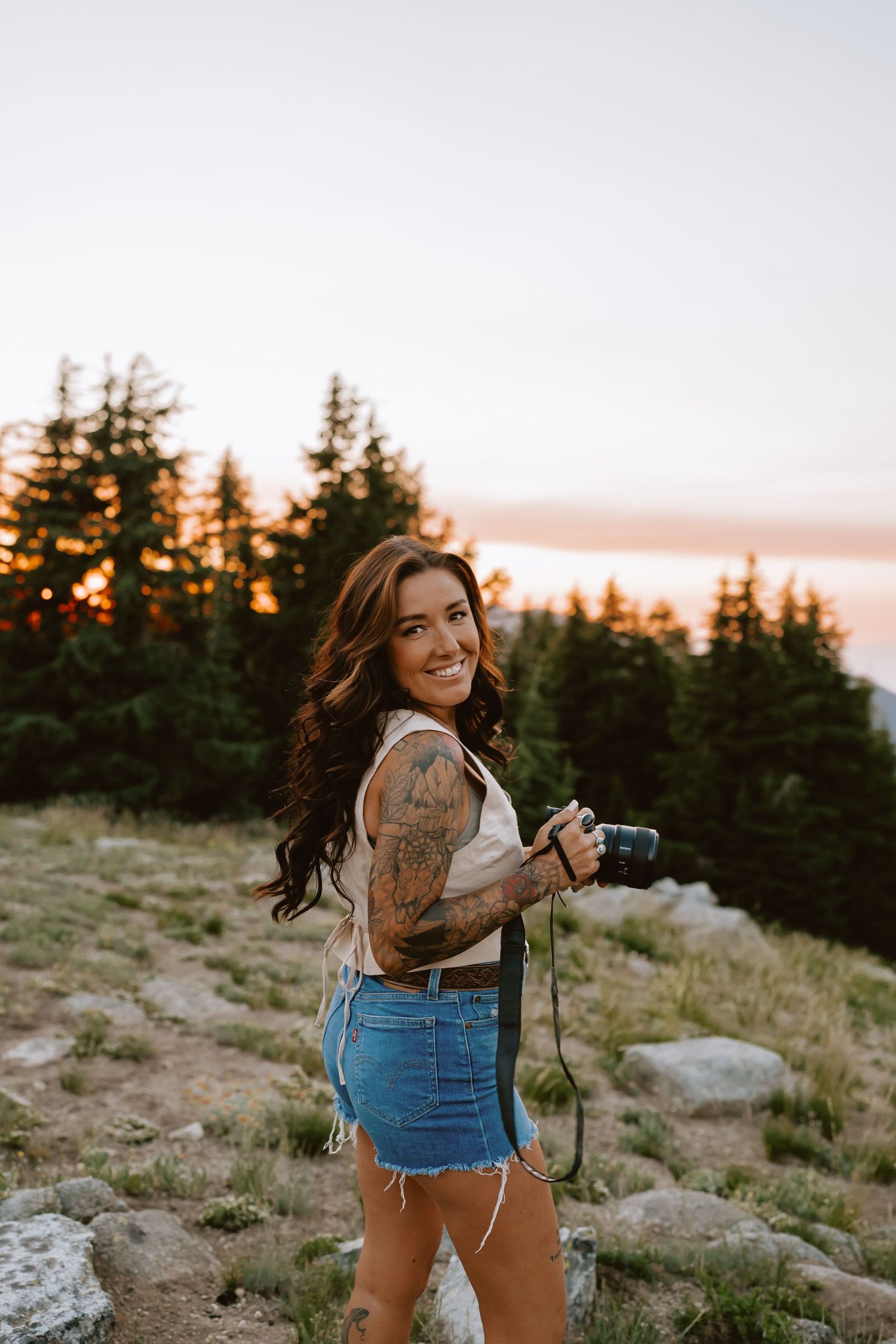 Mountain sunset photography session with vintage camera and denim outfit.