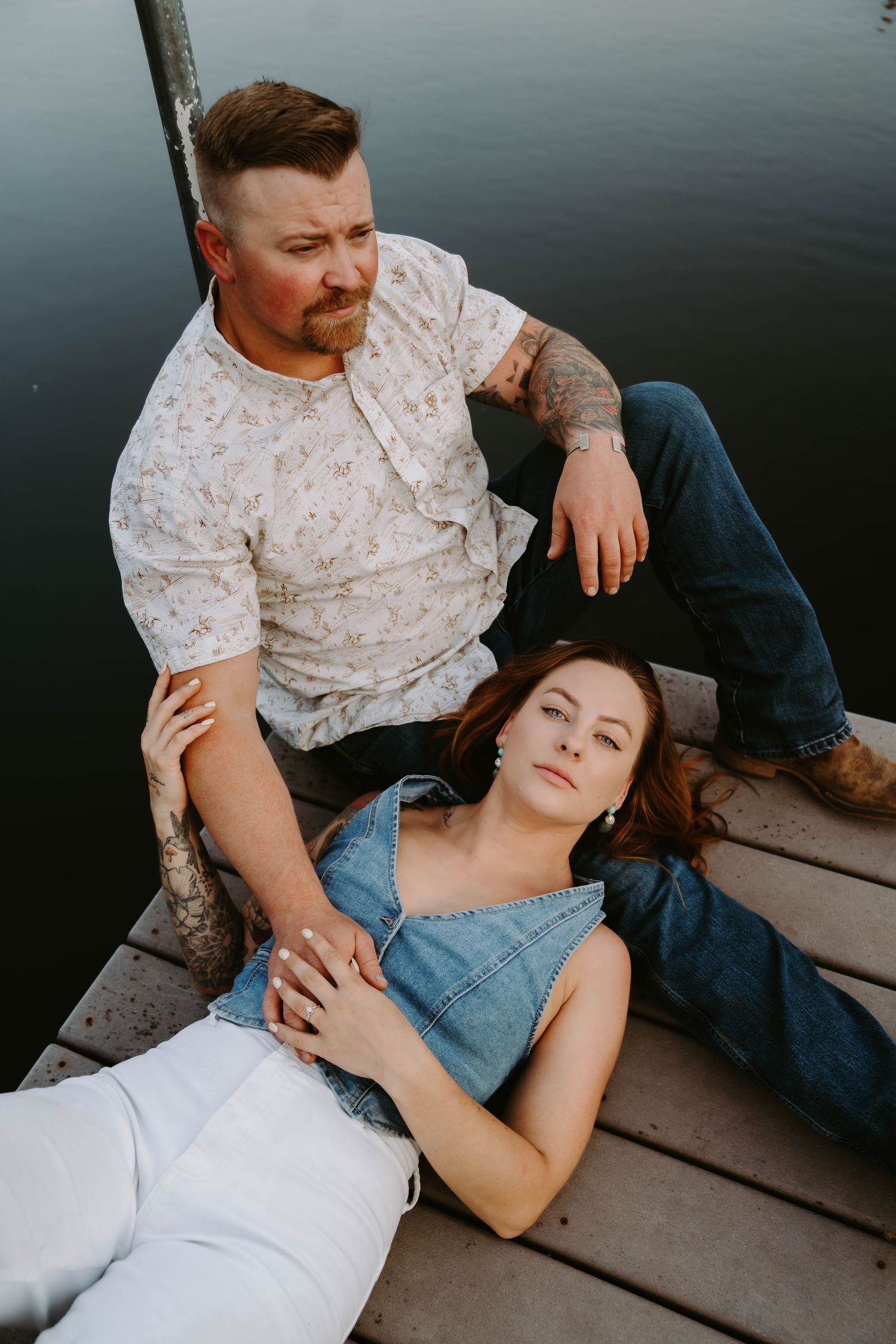 A couple shares an intimate moment while resting on a lakeside dock.
