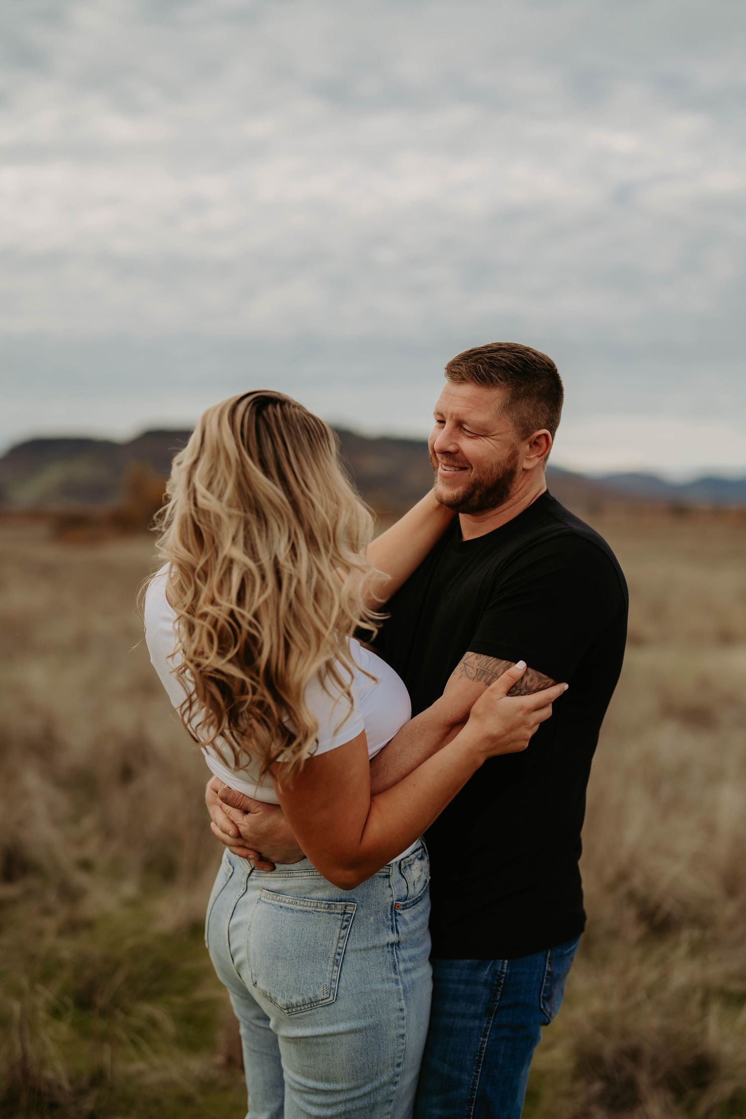 Intimate couple portraits in desert setting with cloudy sky.