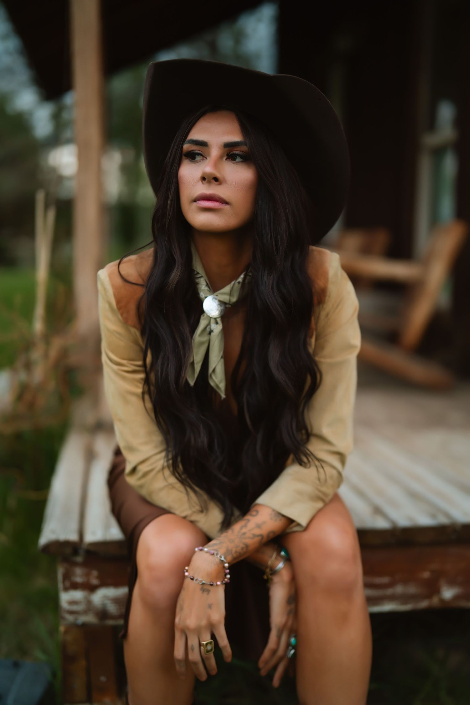 Stylish western photoshoot featuring a wide-brimmed black hat and beige jacket.