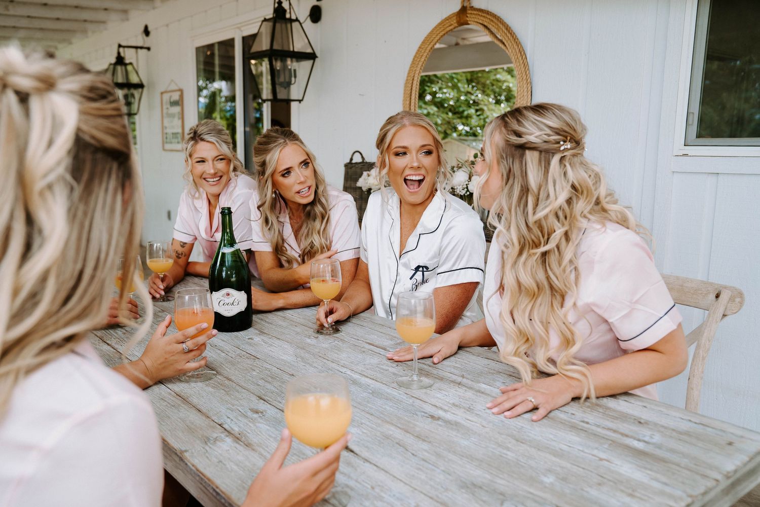 Friends gathered on a wooden deck sharing drinks and laughter in casual setting.