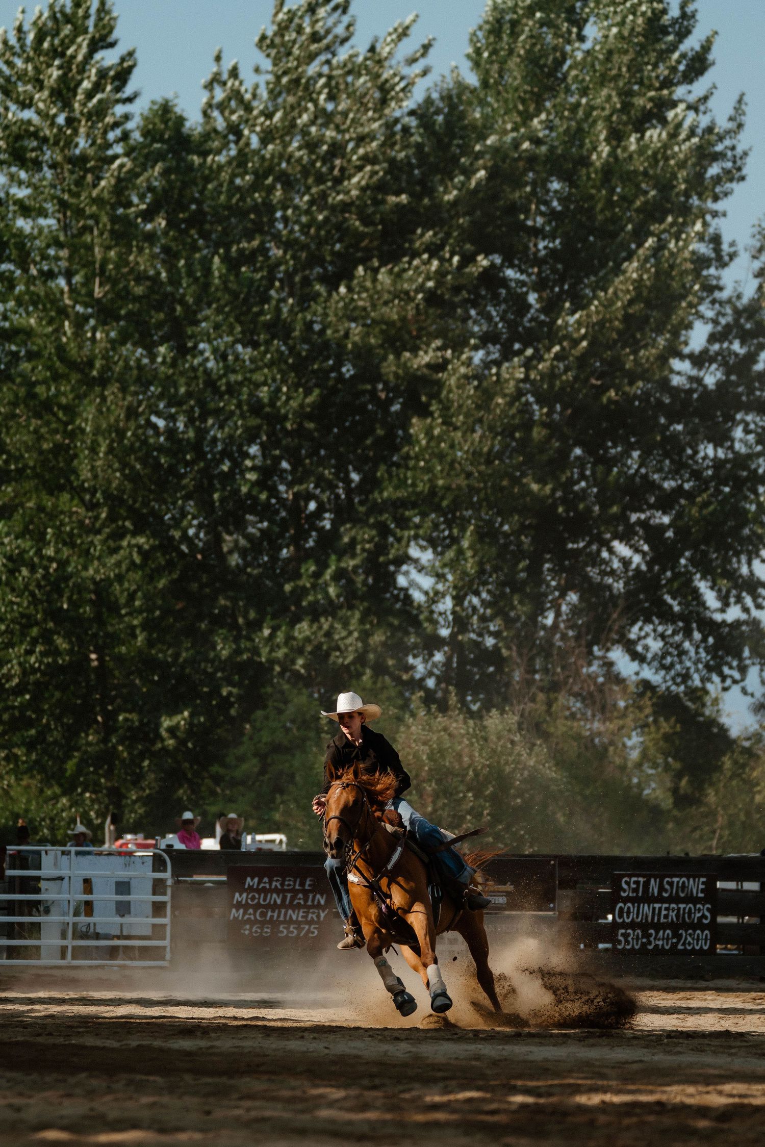 Dynamic shot of barrel racing competition with horse and rider racing through an outdoor arena.