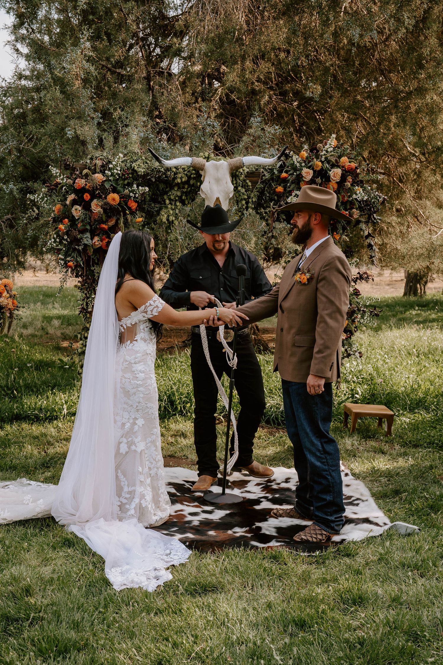 Outdoor wedding ceremony taking place on grass with rustic western-themed details.