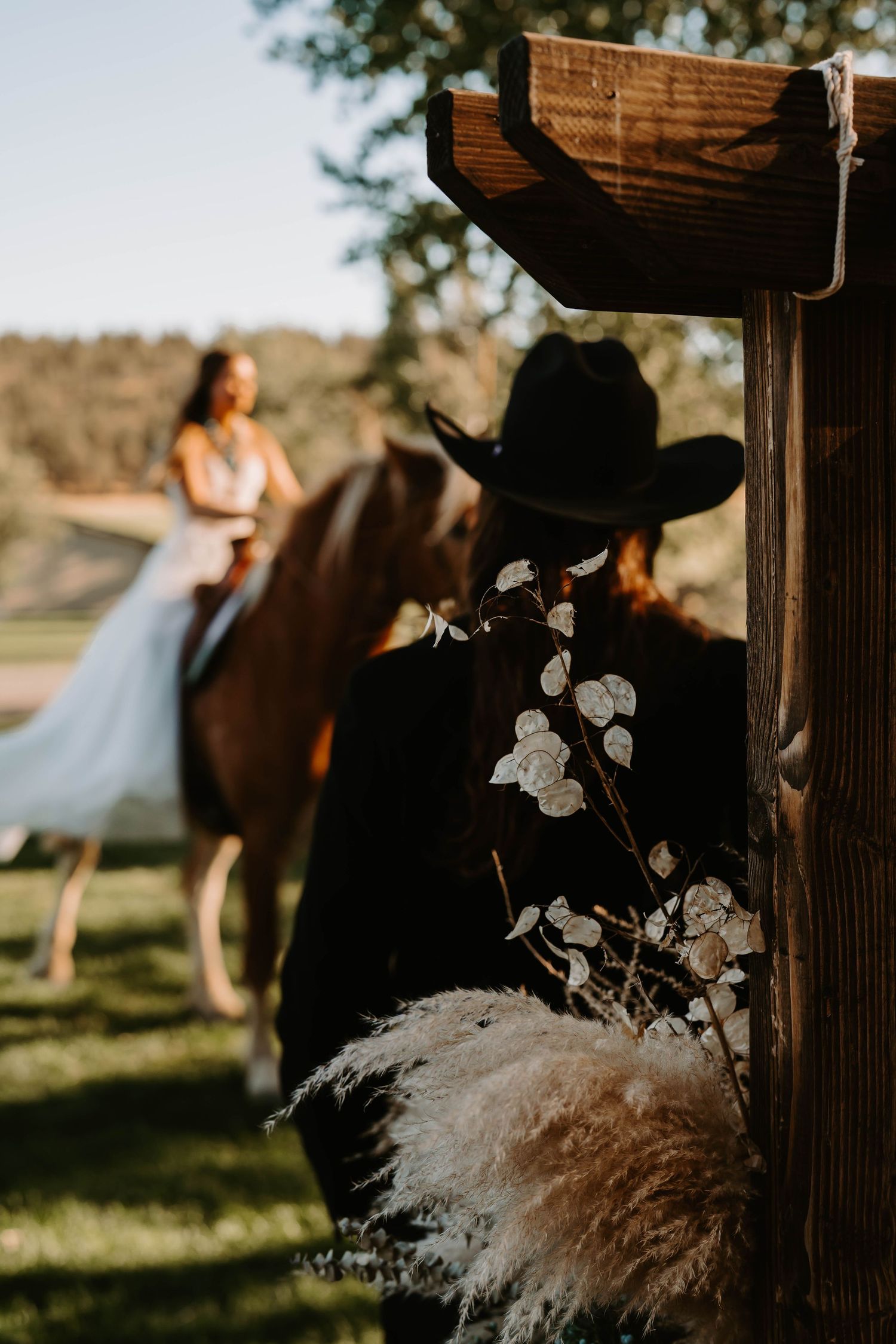 Dreamy wedding scene with pampas grass decorations and soft sunlight filtering through wooden posts.