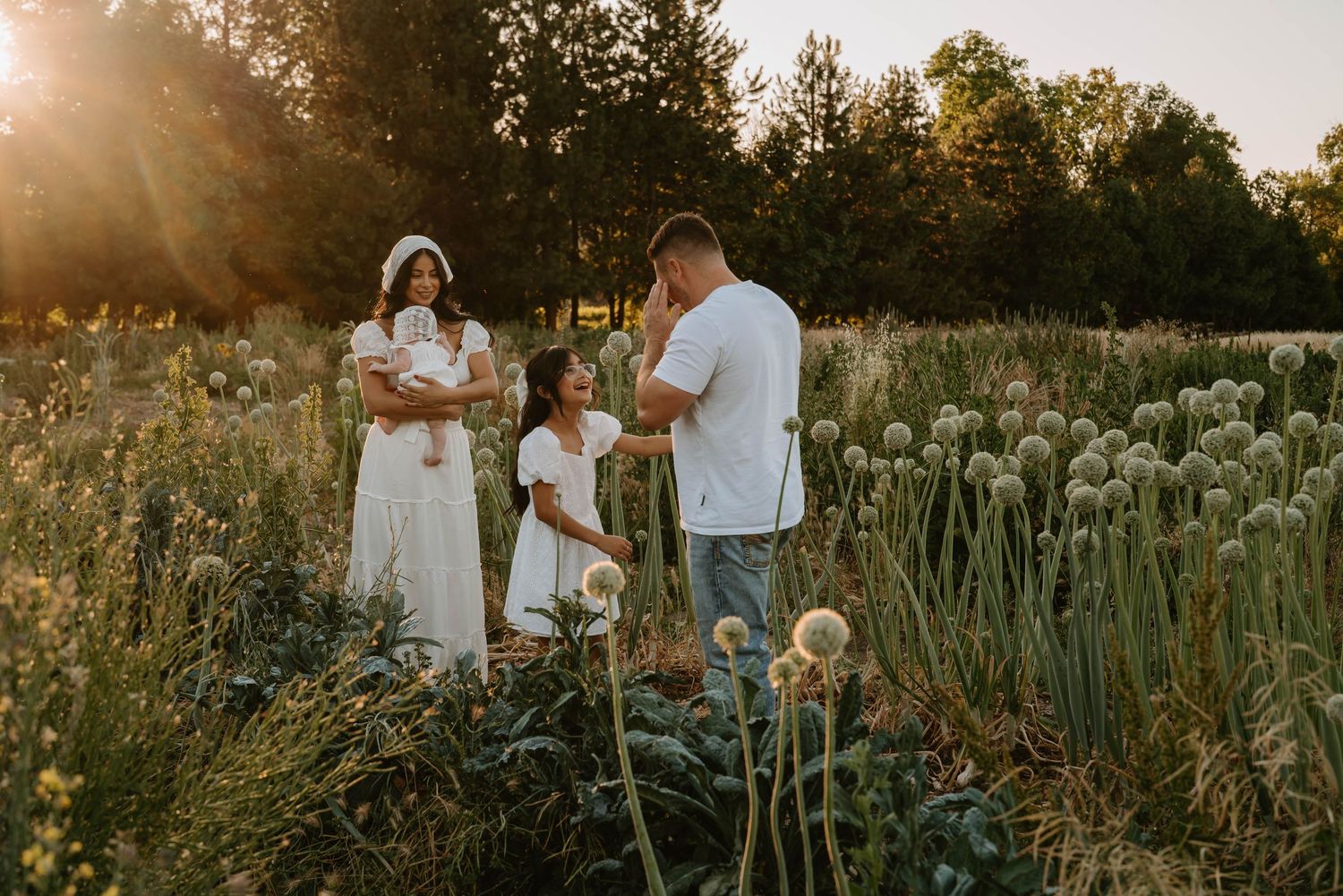 Candid family photos taken at sunset in a field with tall grass and flowers.