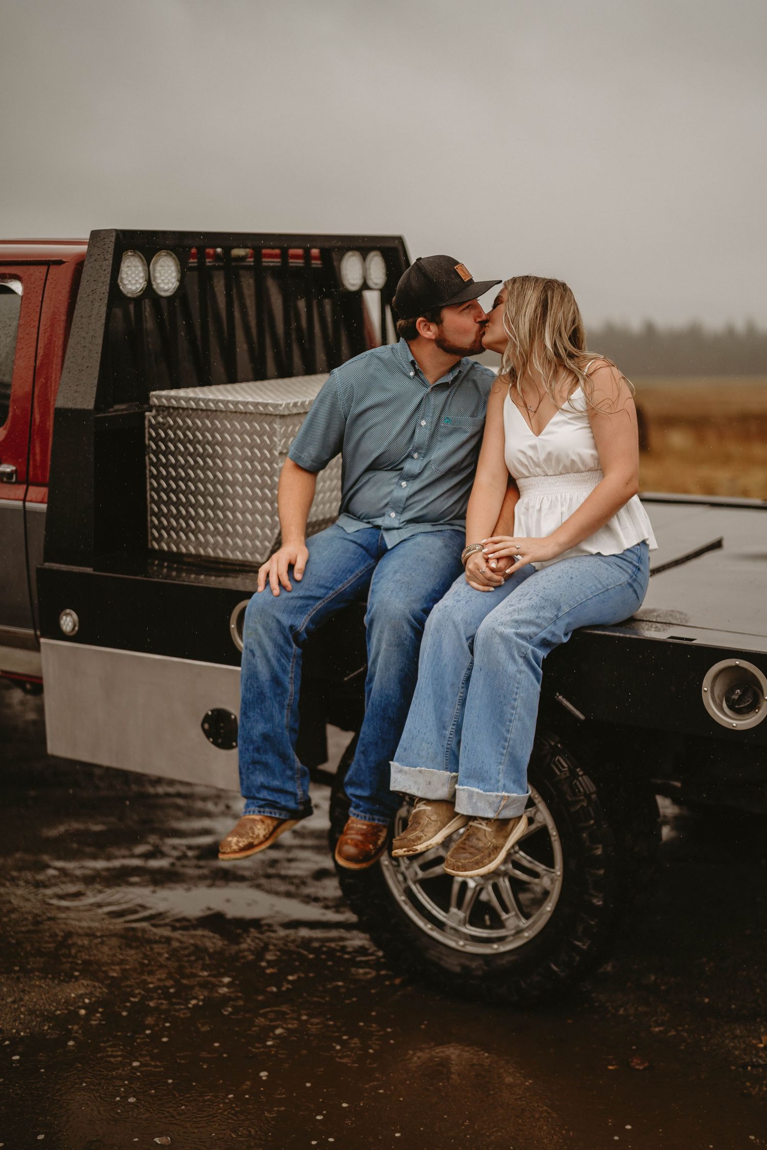 Couple sitting together on the tailgate of a vintage pickup truck at sunset.