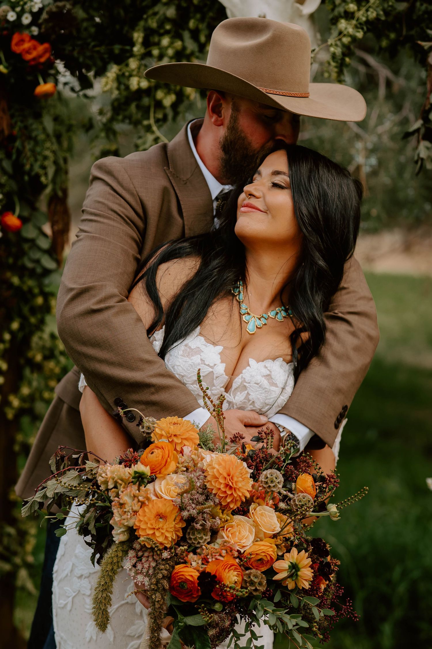 A western-themed wedding photo with autumn-colored florals and turquoise jewelry.