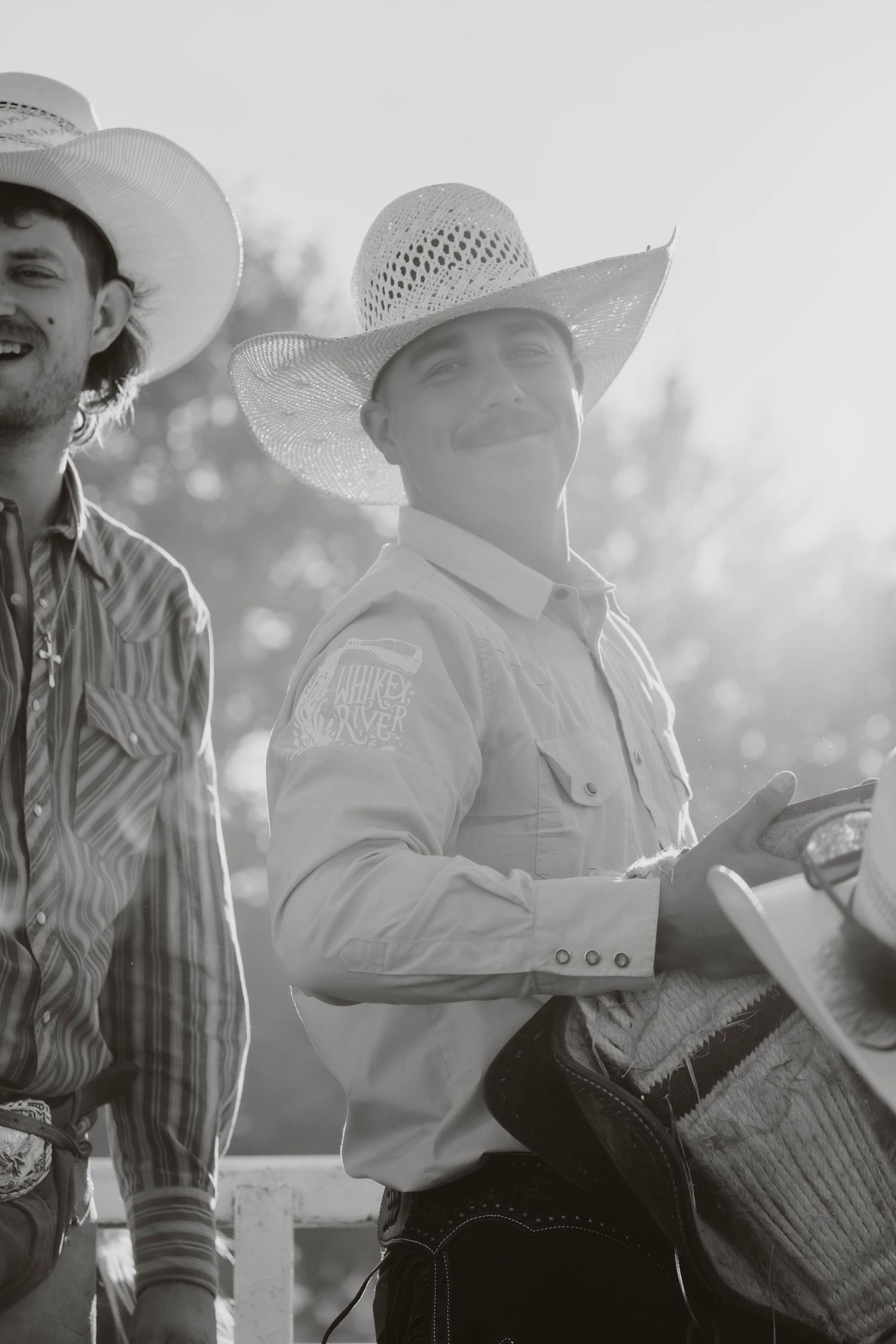 Cowboys in white hats and western attire sitting together at a rodeo event.
