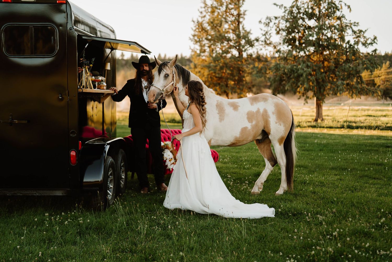 Rustic outdoor wedding scene with horses and vintage truck in golden field.