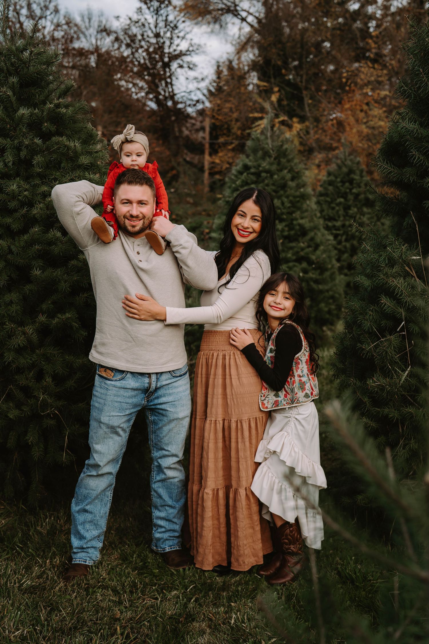 Playful outdoor family photoshoot in a wooded setting during autumn.