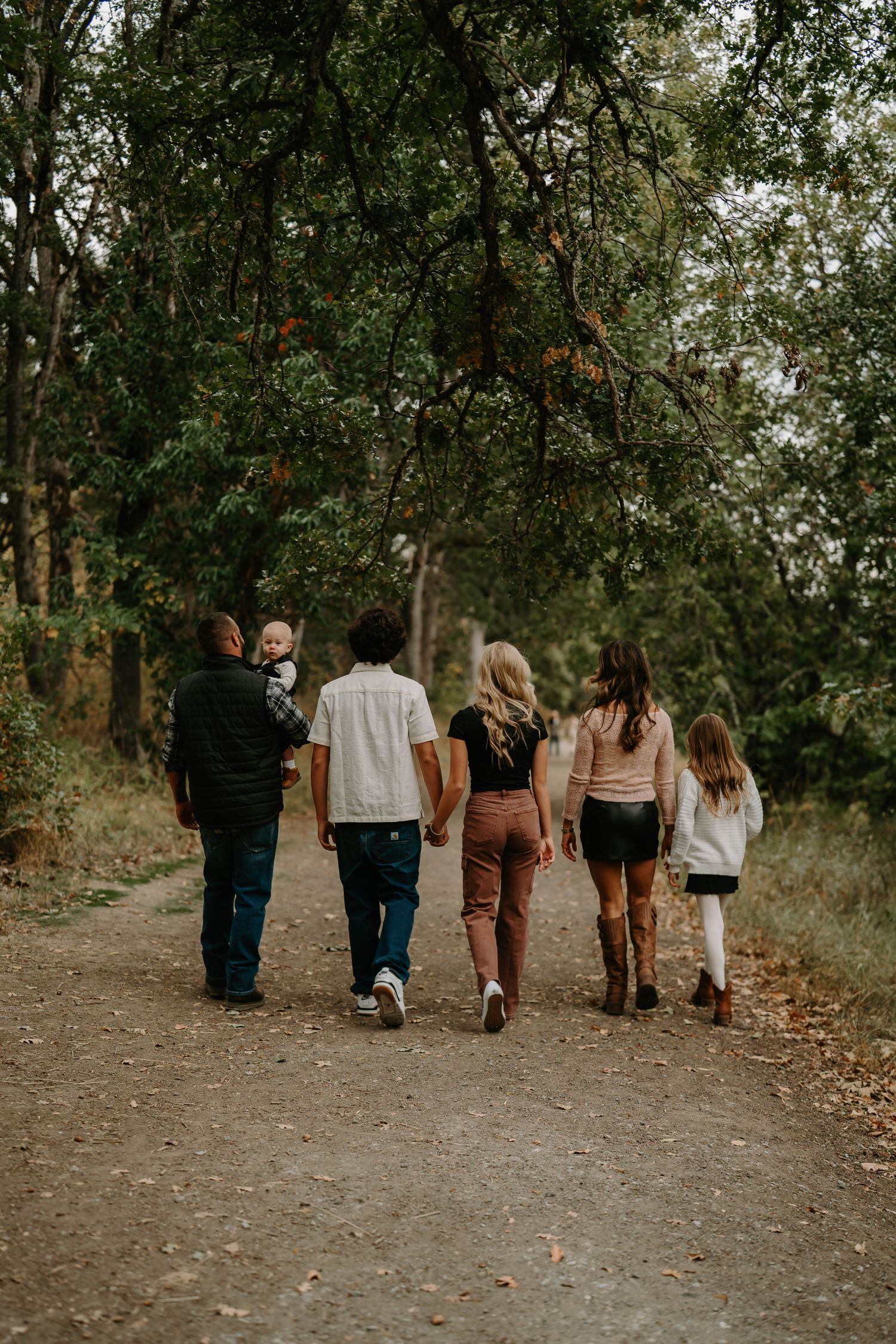 Group walking away from camera through a wooded path during autumn.