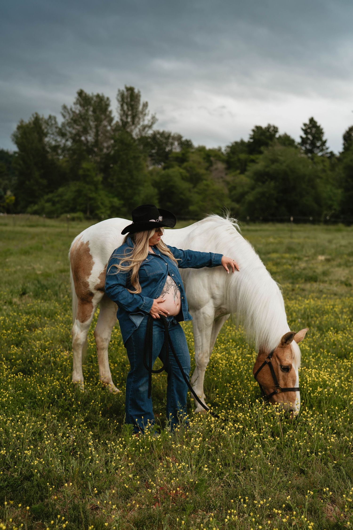 White horse grazing in a wildflower meadow on an overcast day.