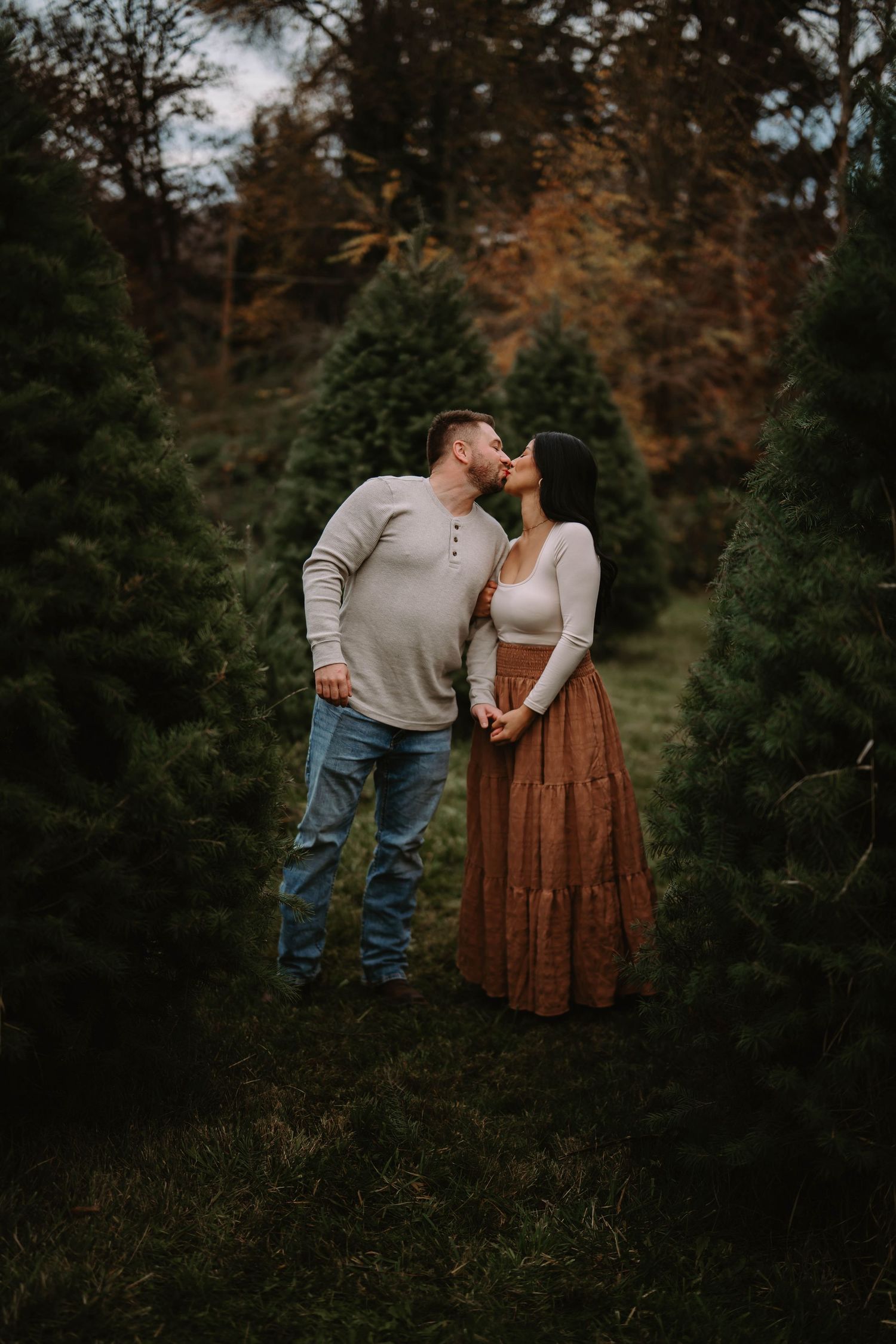 Romantic autumn photoshoot among evergreen trees at Christmas tree farm.