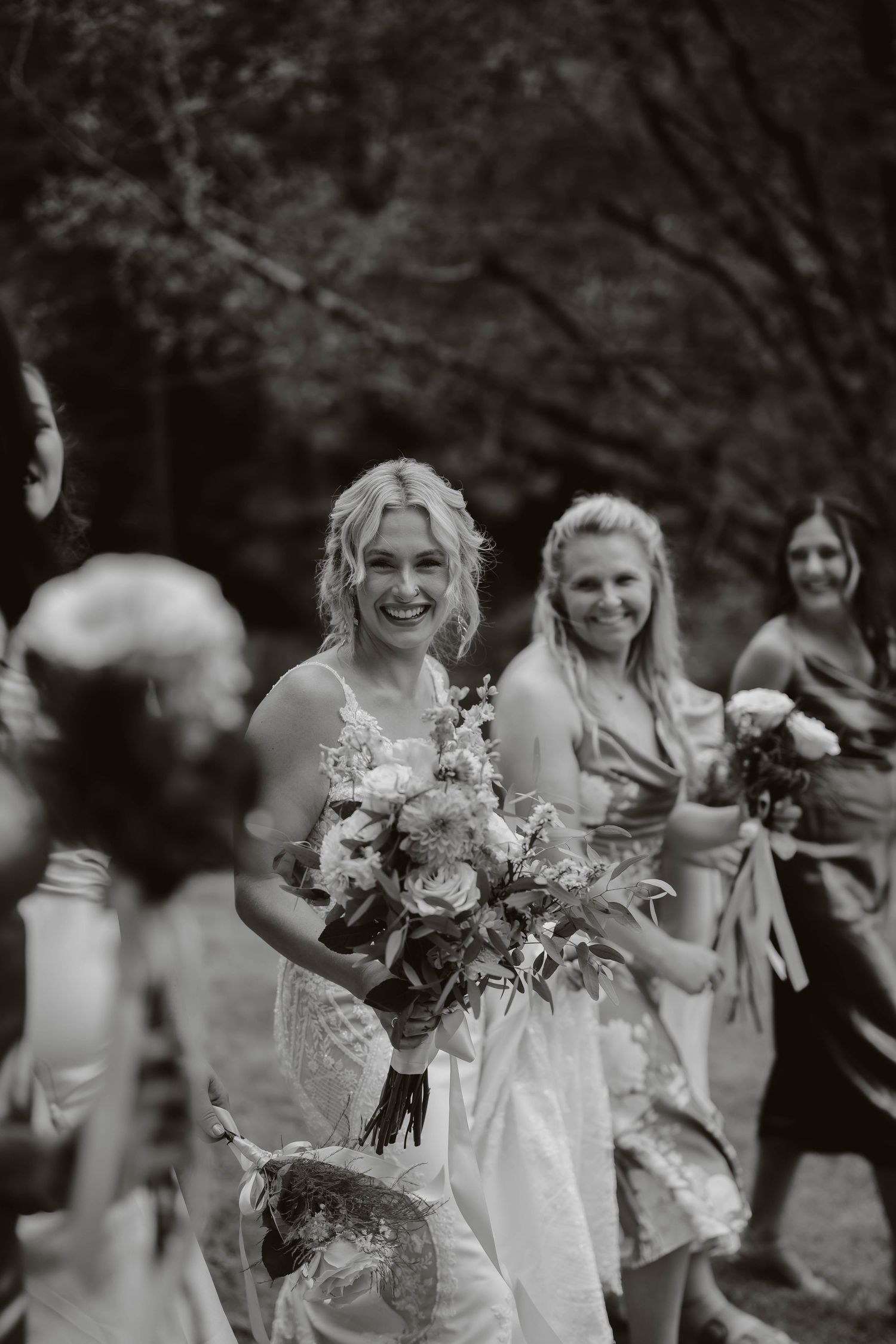 Black and white photo of bridal party laughing together while holding bouquets.