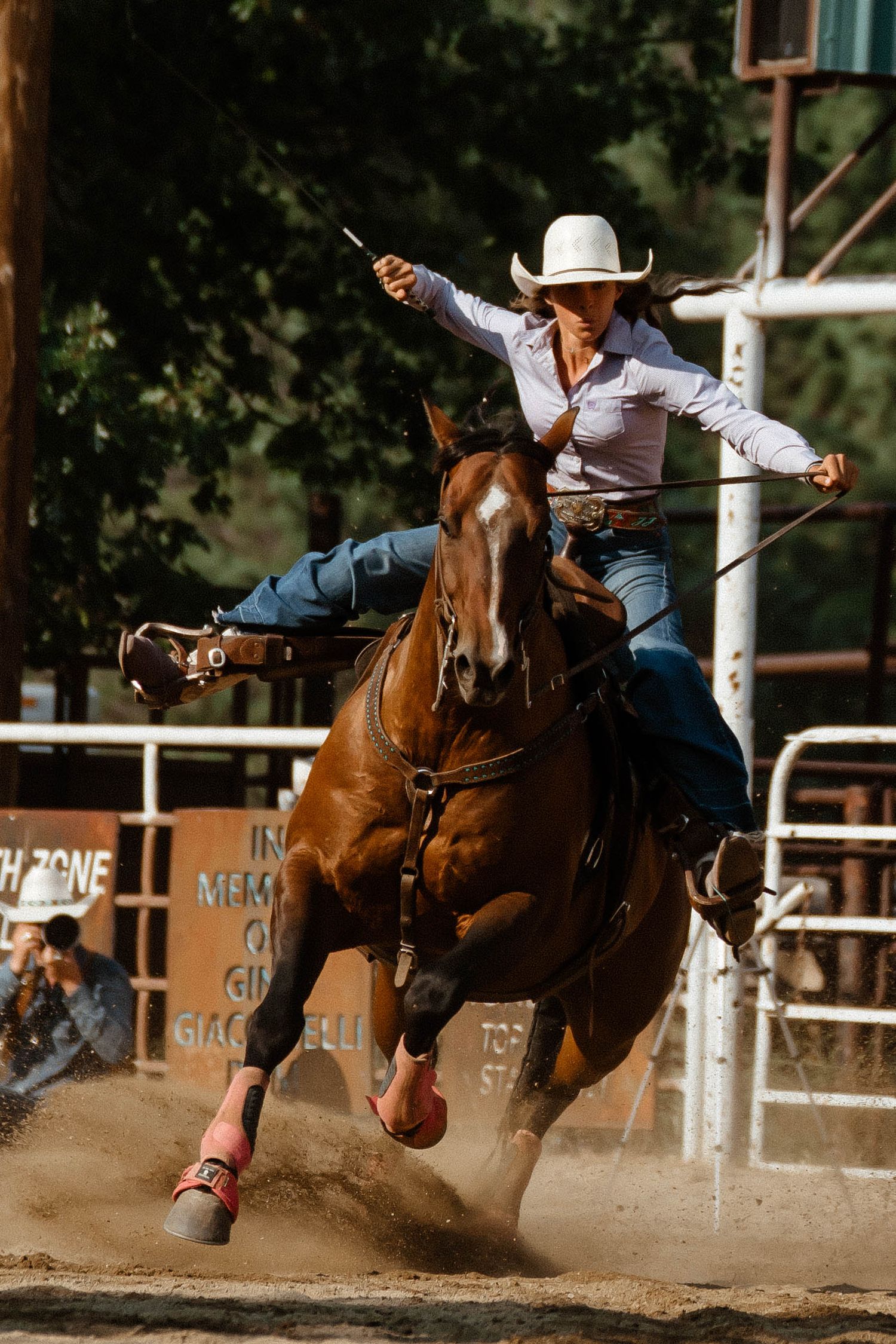 Action shot of barrel racing competition with horse and rider making a sharp turn around a barrel.