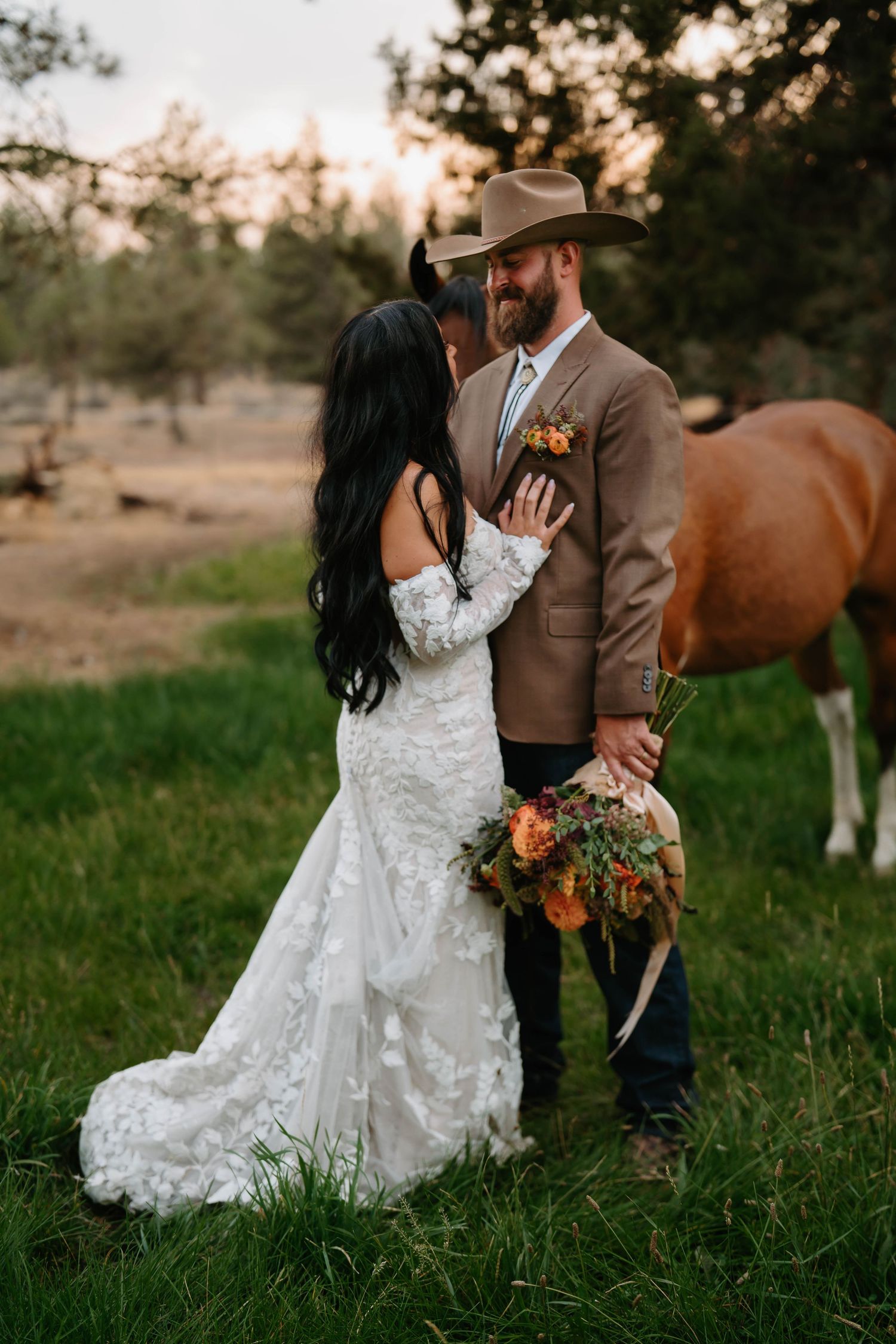 Romantic wedding portraits in a field at sunset with a horse in the background.