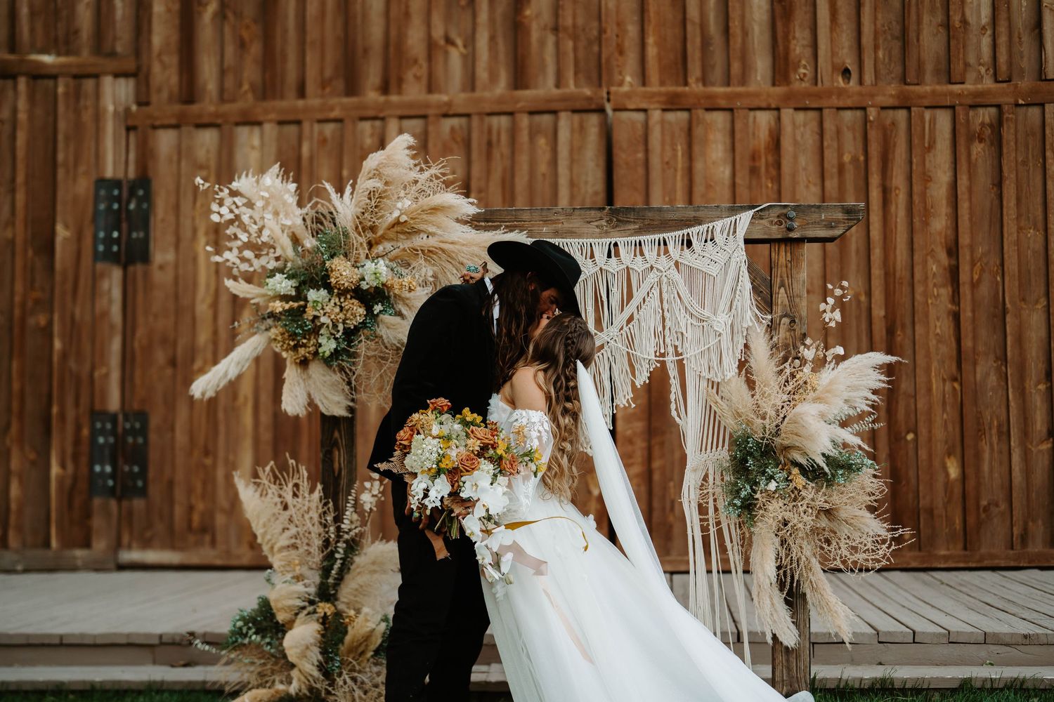 Rustic barn wedding decor with macrame banners and dried floral arrangements.