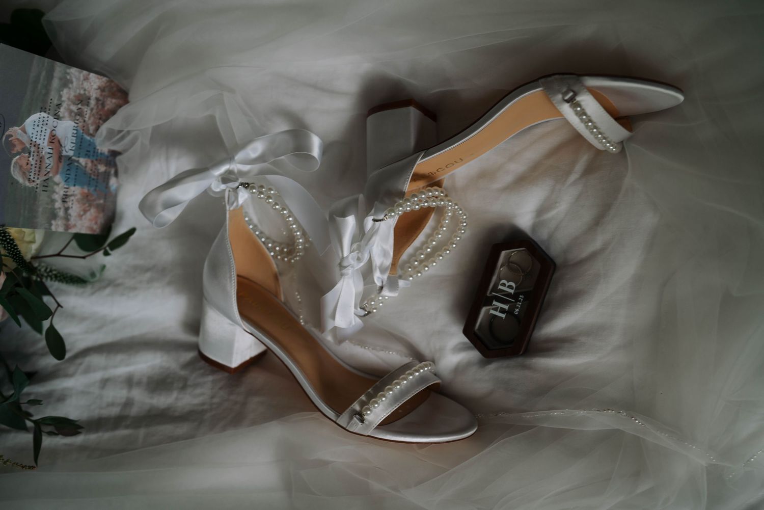 Elegant bridal shoes and accessories arranged on white fabric.