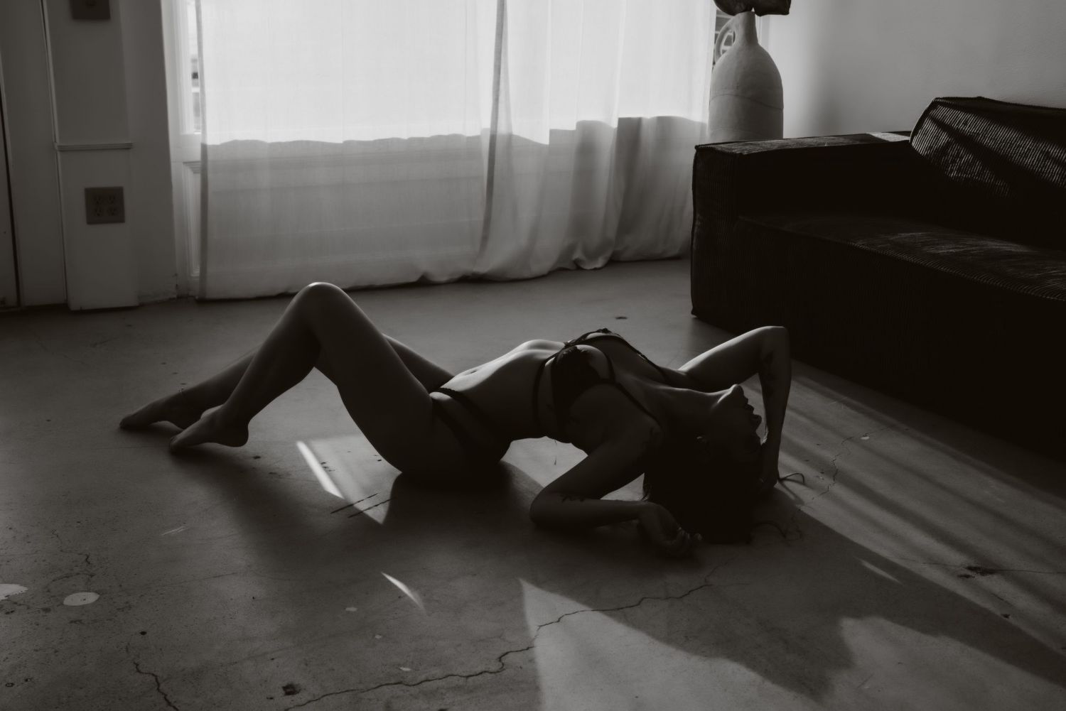 Black and white artistic portrait session in a minimalist indoor setting.
