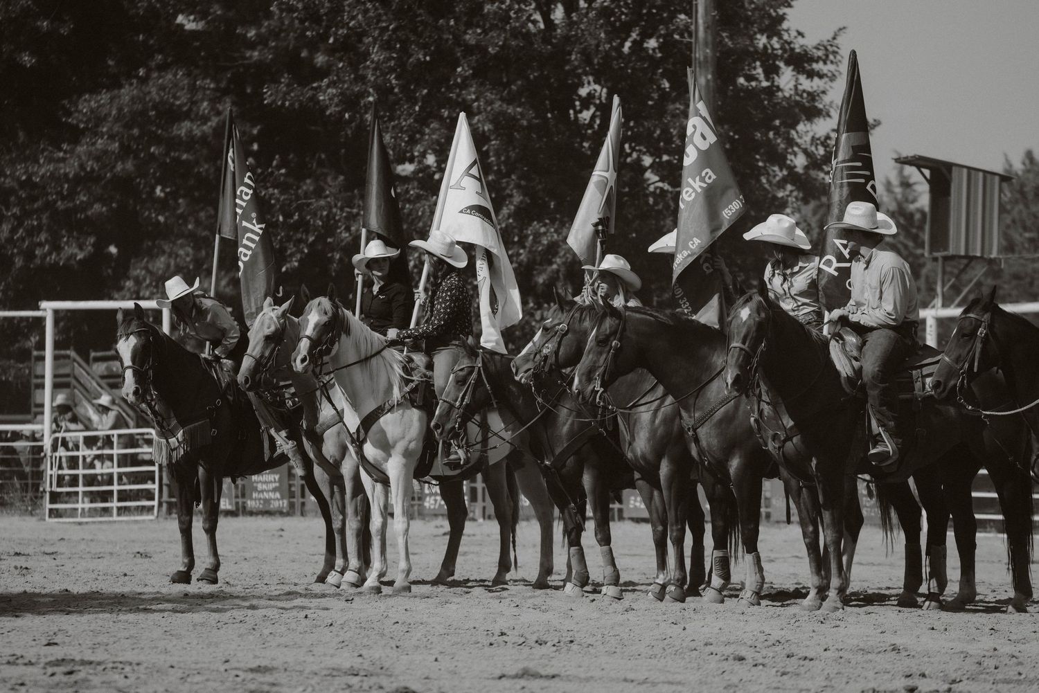 A line of riders on horseback performing in an arena during a western show.