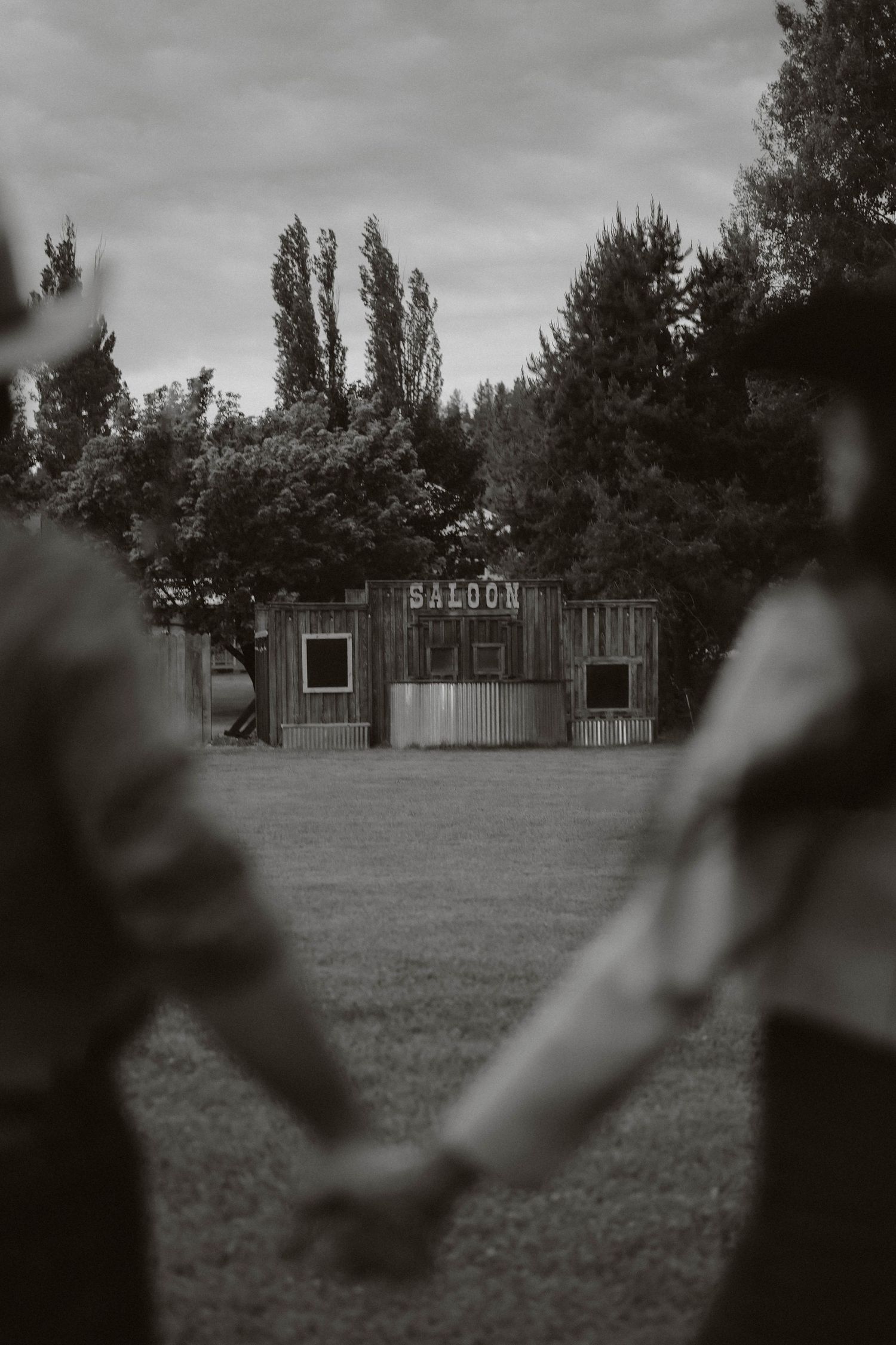 A black and white landscape photo shows a distant saloon building across an open field.