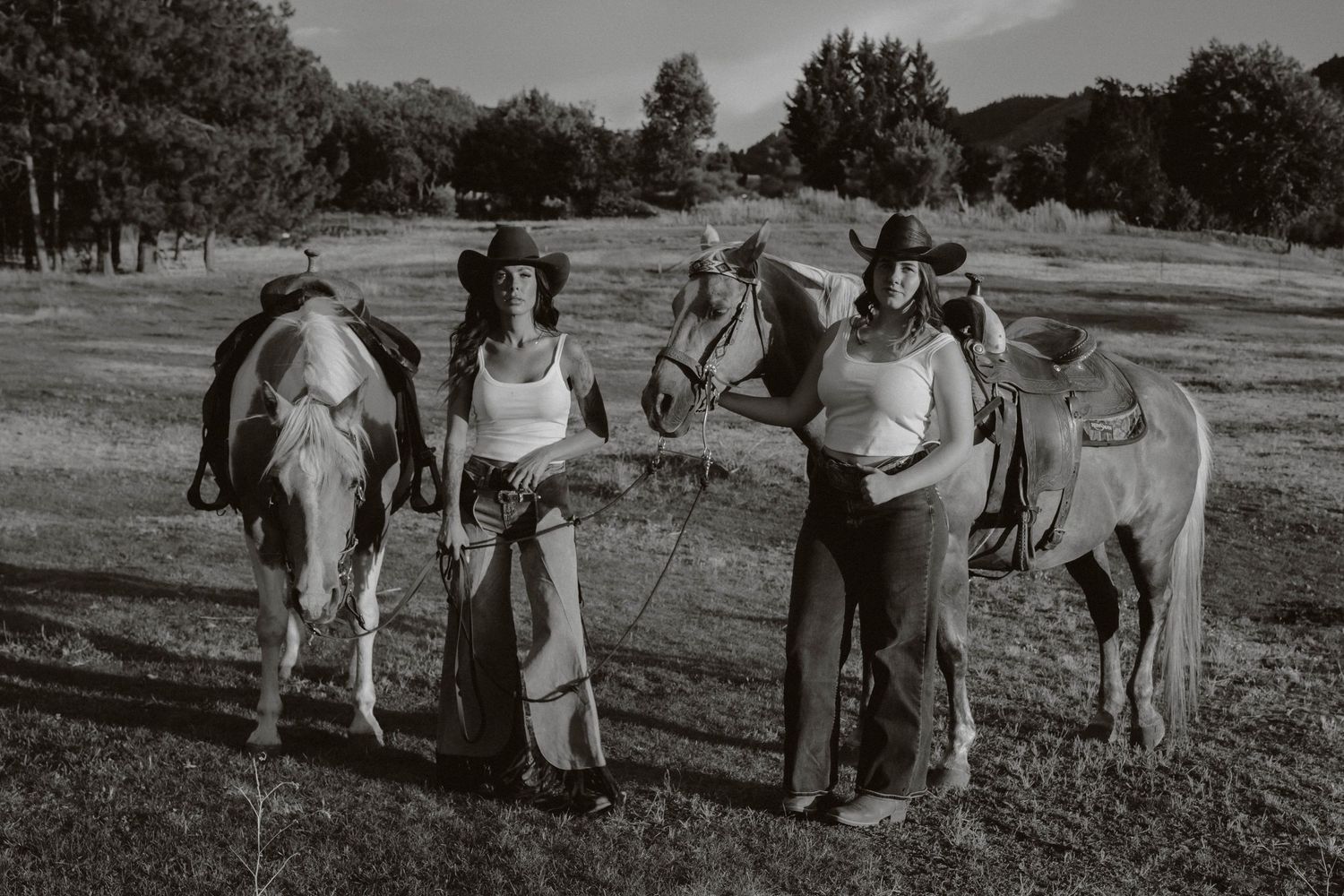 Group gathered with horses in a black and white countryside scene.