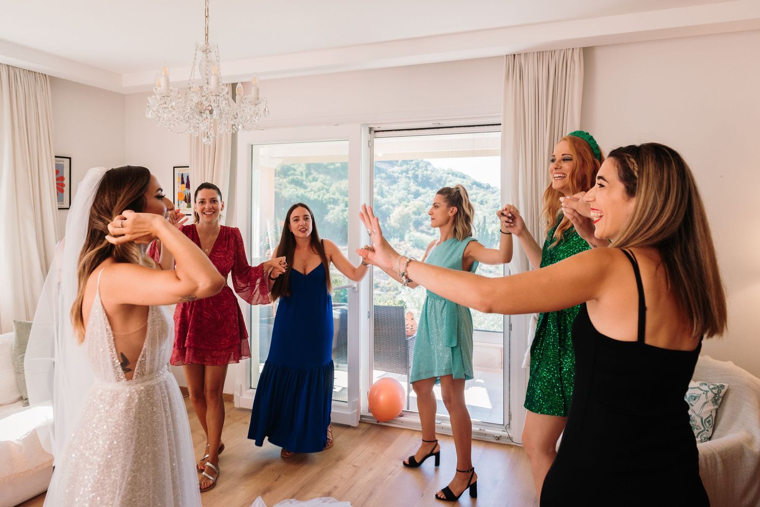 A festive indoor celebration scene with people in colorful dresses forming a line.